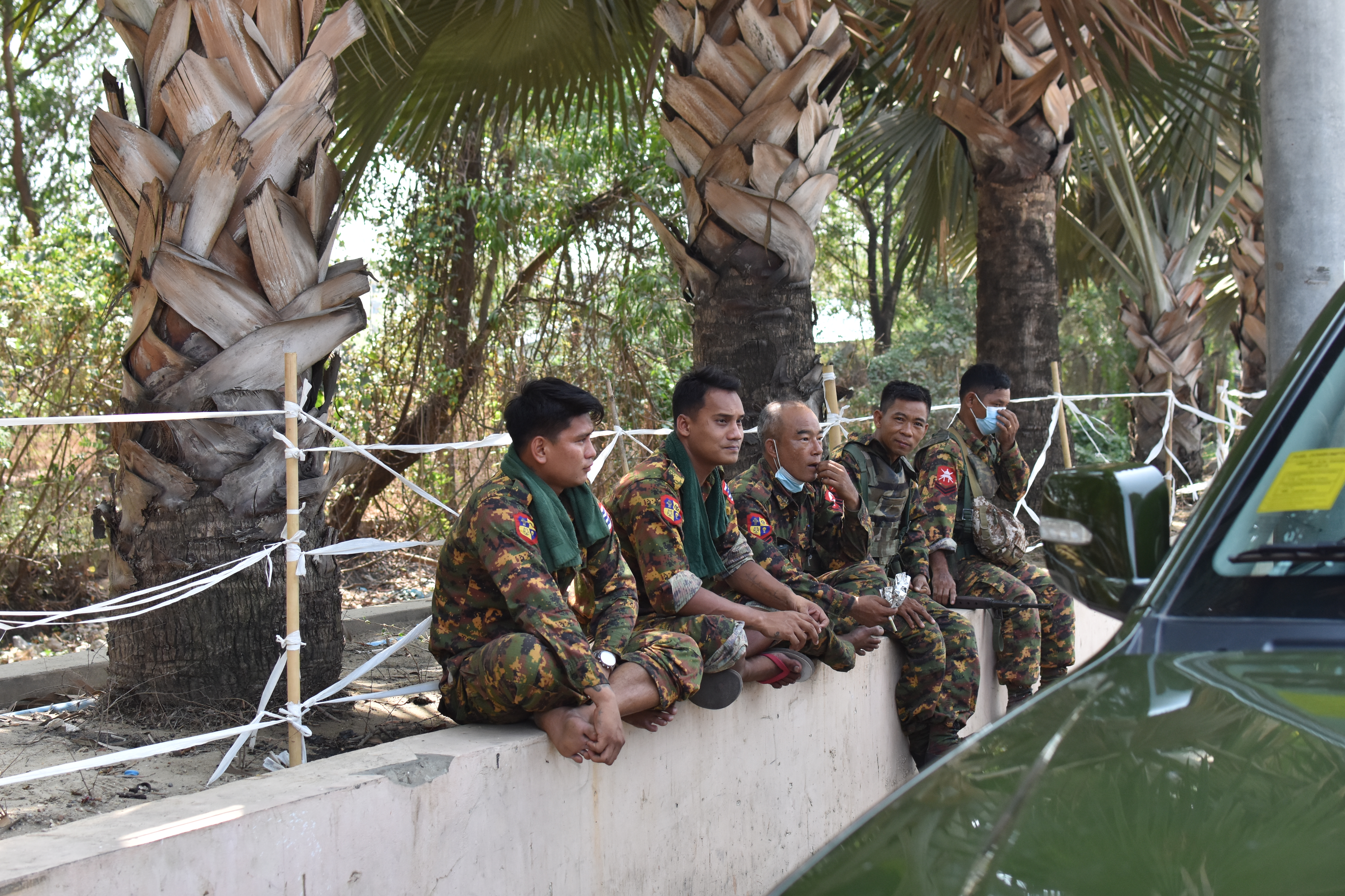 Military soldiers from the convoy accompanying the press tour waiting on the side of the road in Hlaing Thar Yar. March 31, 202