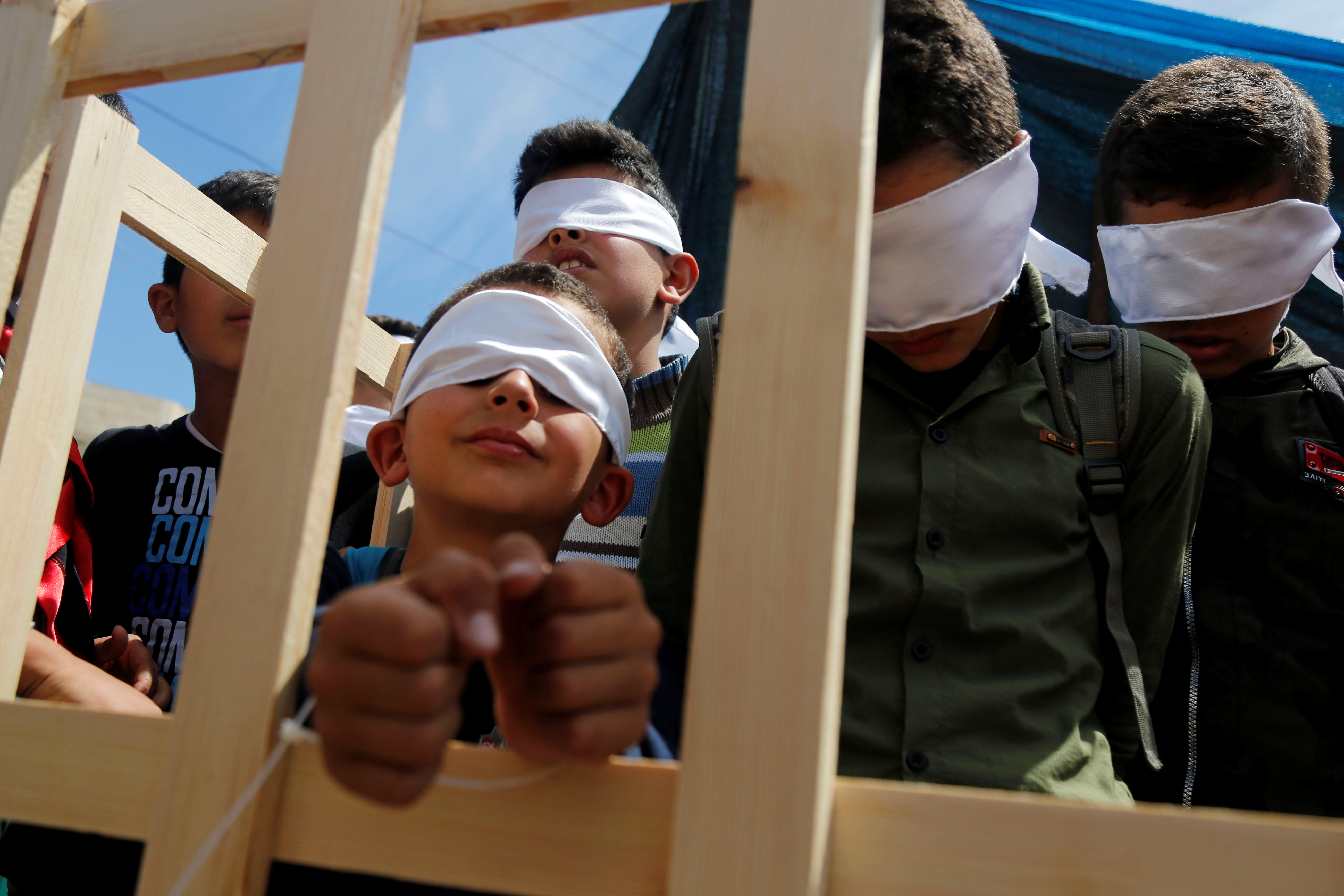 Blindfolded boys play the role of prisoners during a rally marking Palestinian Prisoners' Day [File: Raneen Sawafta/Reuters]