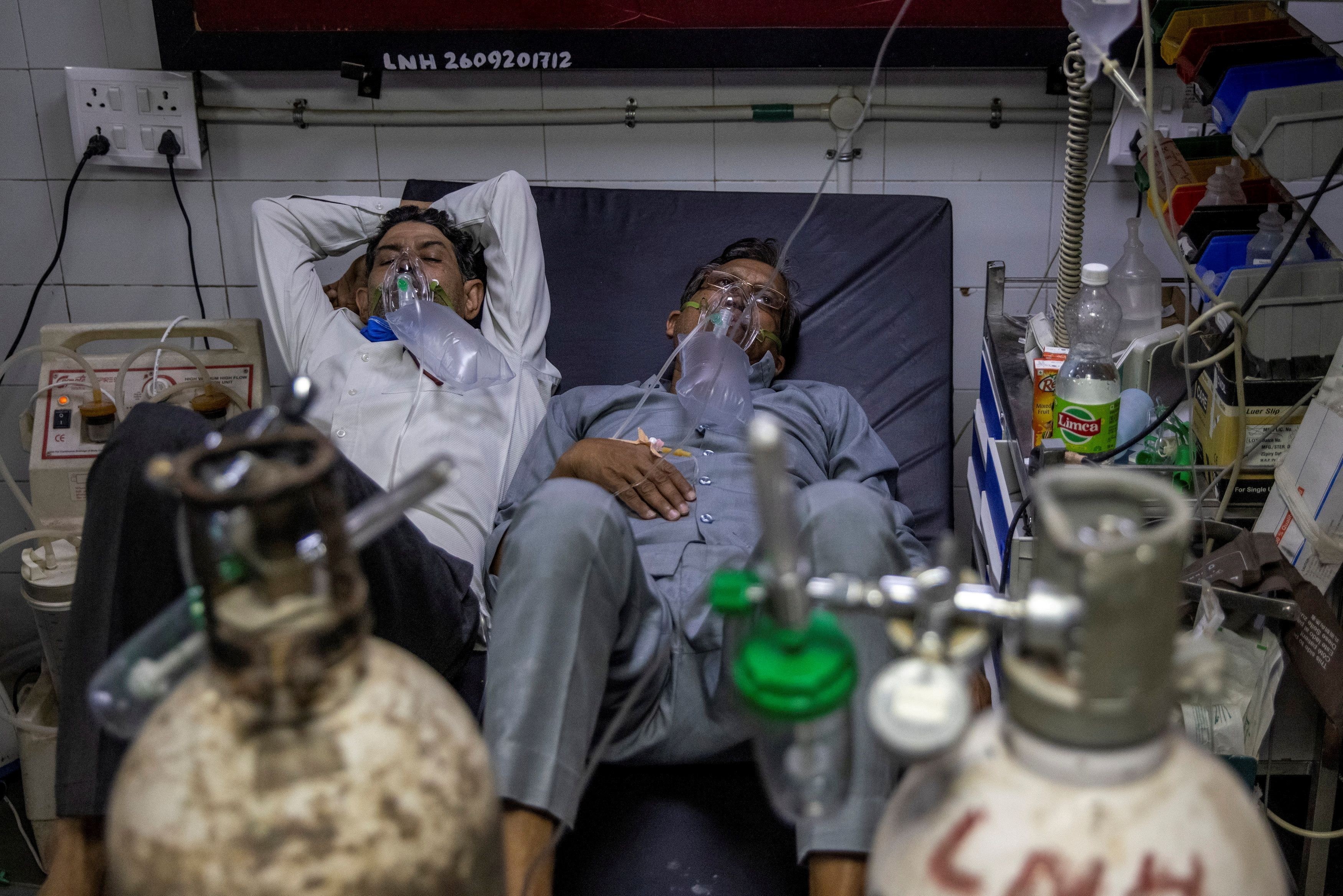 Patients suffering from COVID-19 share a hospital bed in New Delhi