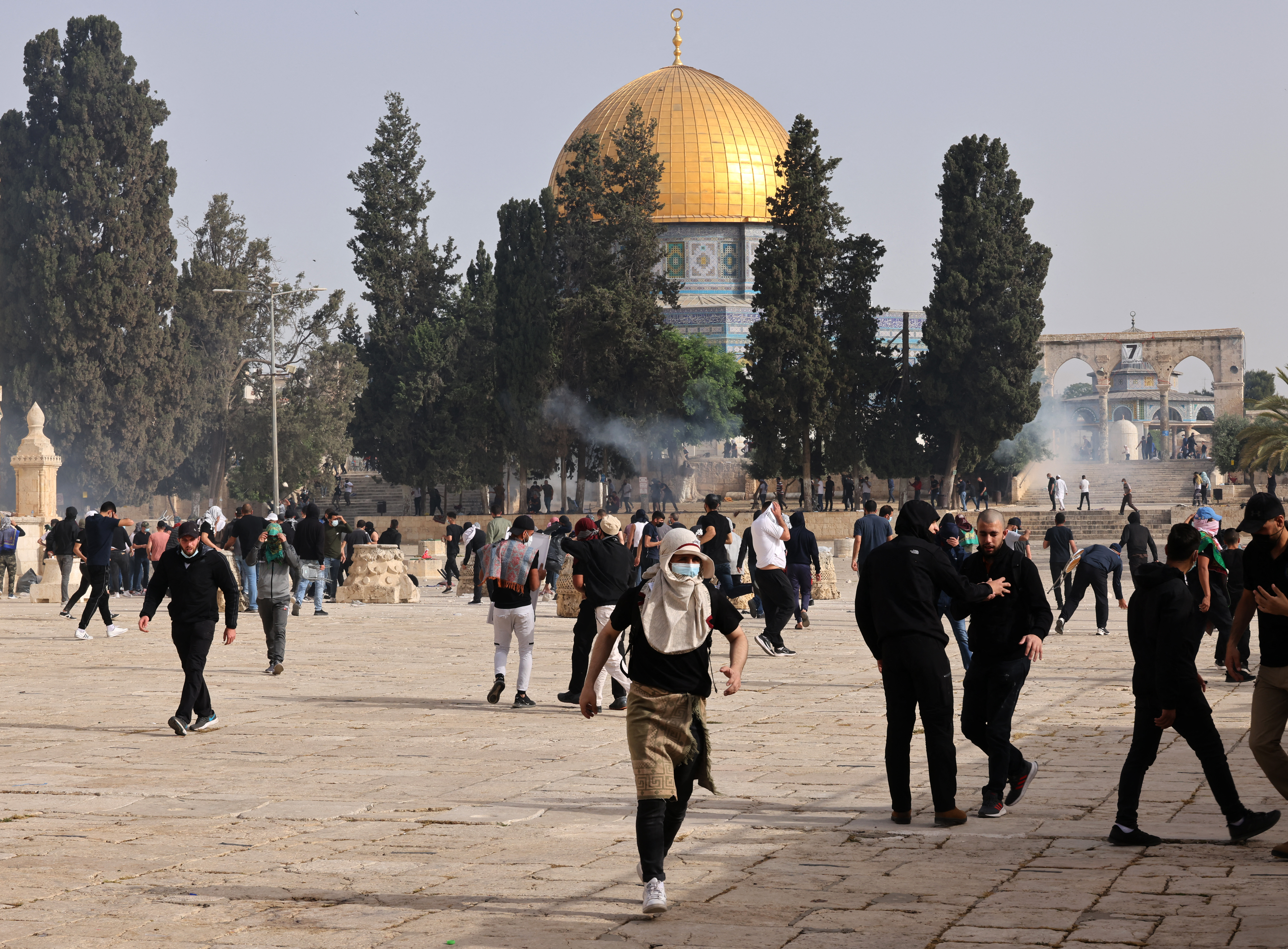 Palestinians run for cover from tear gas fired by Israeli security forces at Jerusalem’s Al-Aqsa Mosque compound