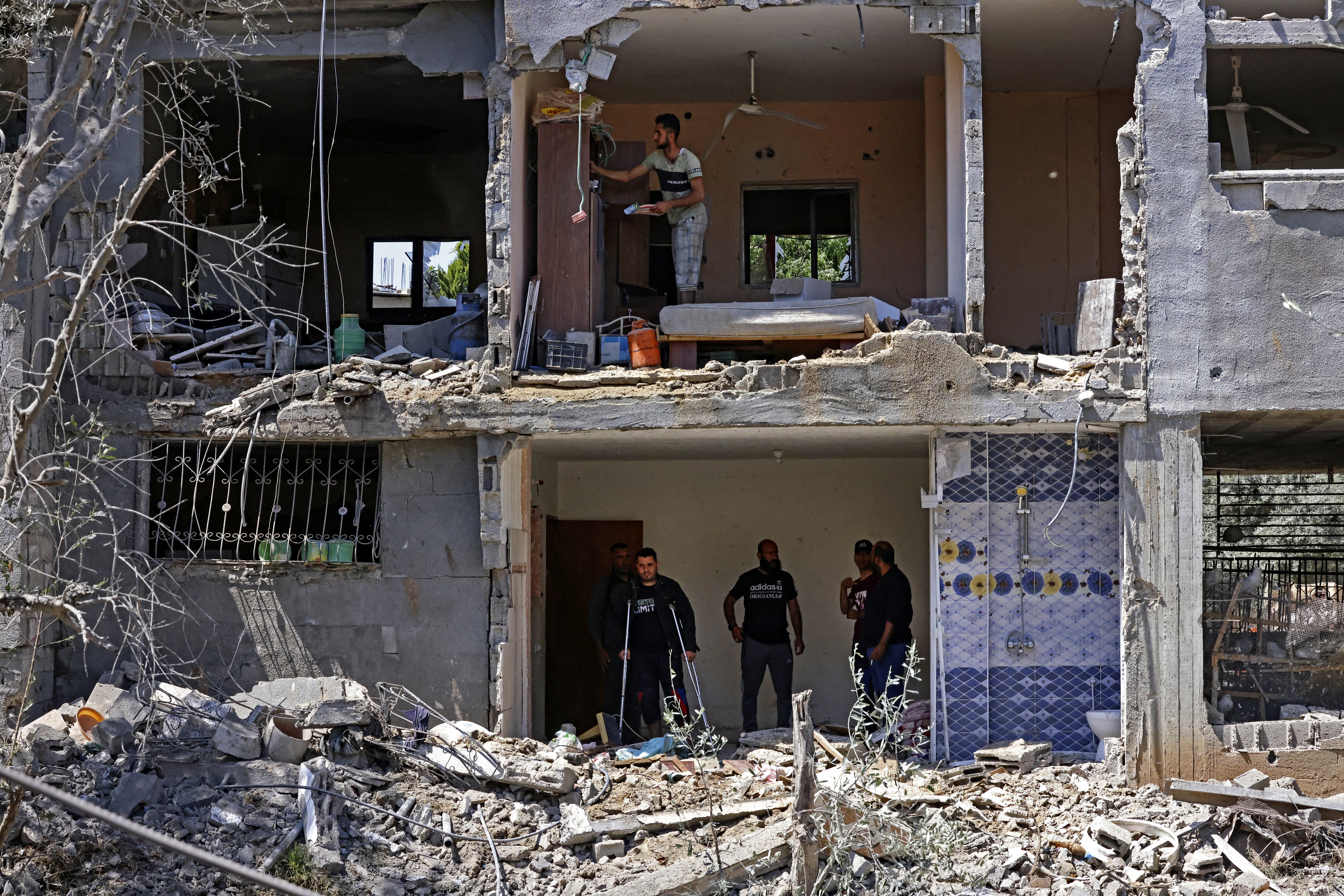 Palestinians assess the damage in a building caused by Israeli air raids, in Beit Hanoun in the northern Gaza Strip, on May 14, 2021