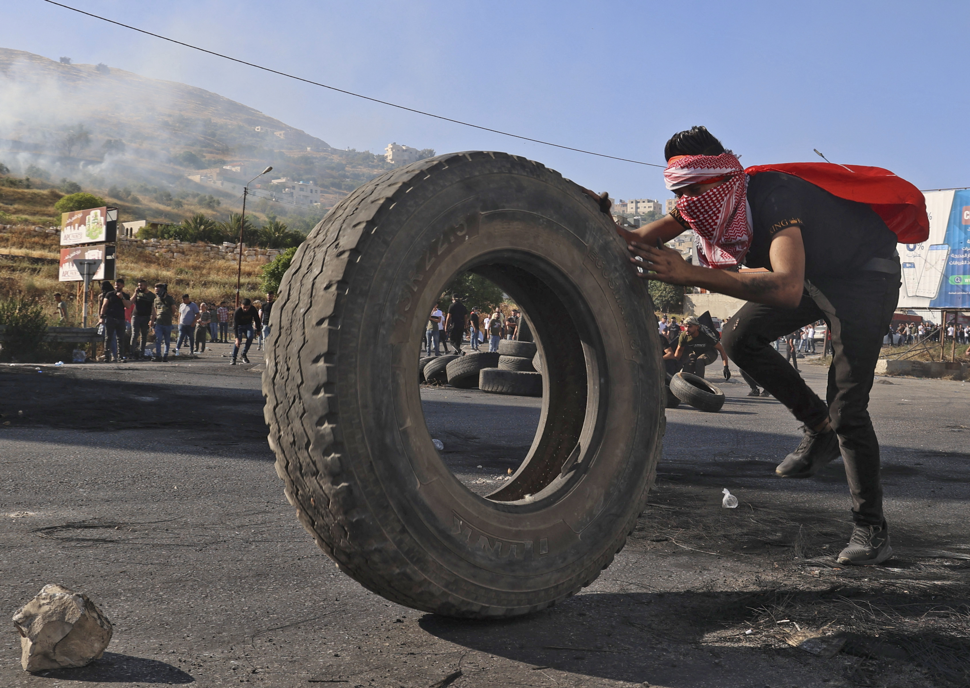 A Palestinian takes cover during clashes with Israeli forces near the Hawara checkpoint south of the occupied West Bank city of Nablus