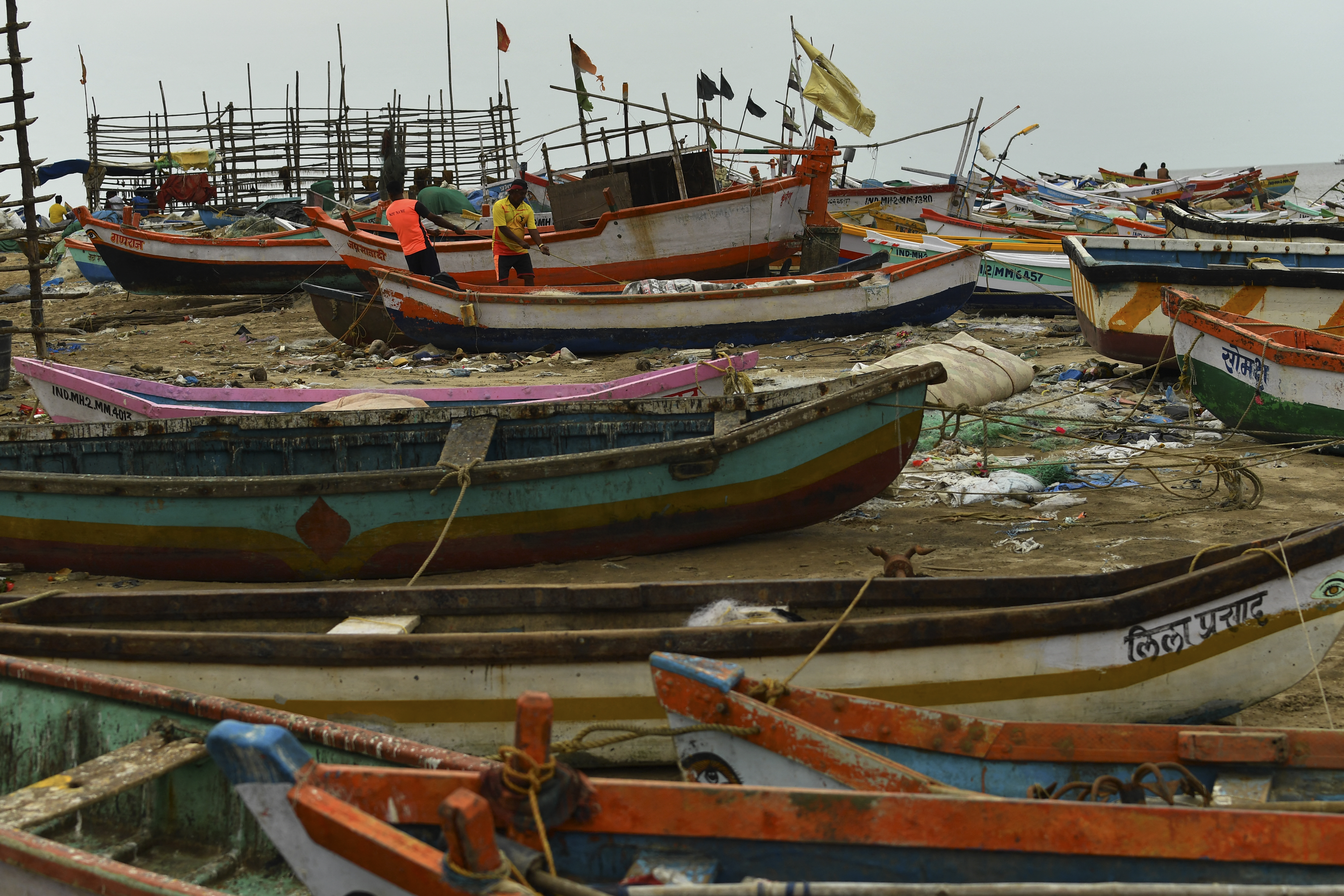 Fishermen are seen next to boats being moored at a fishing village coast in preparation for Cyclone Tauktae in Mumbai