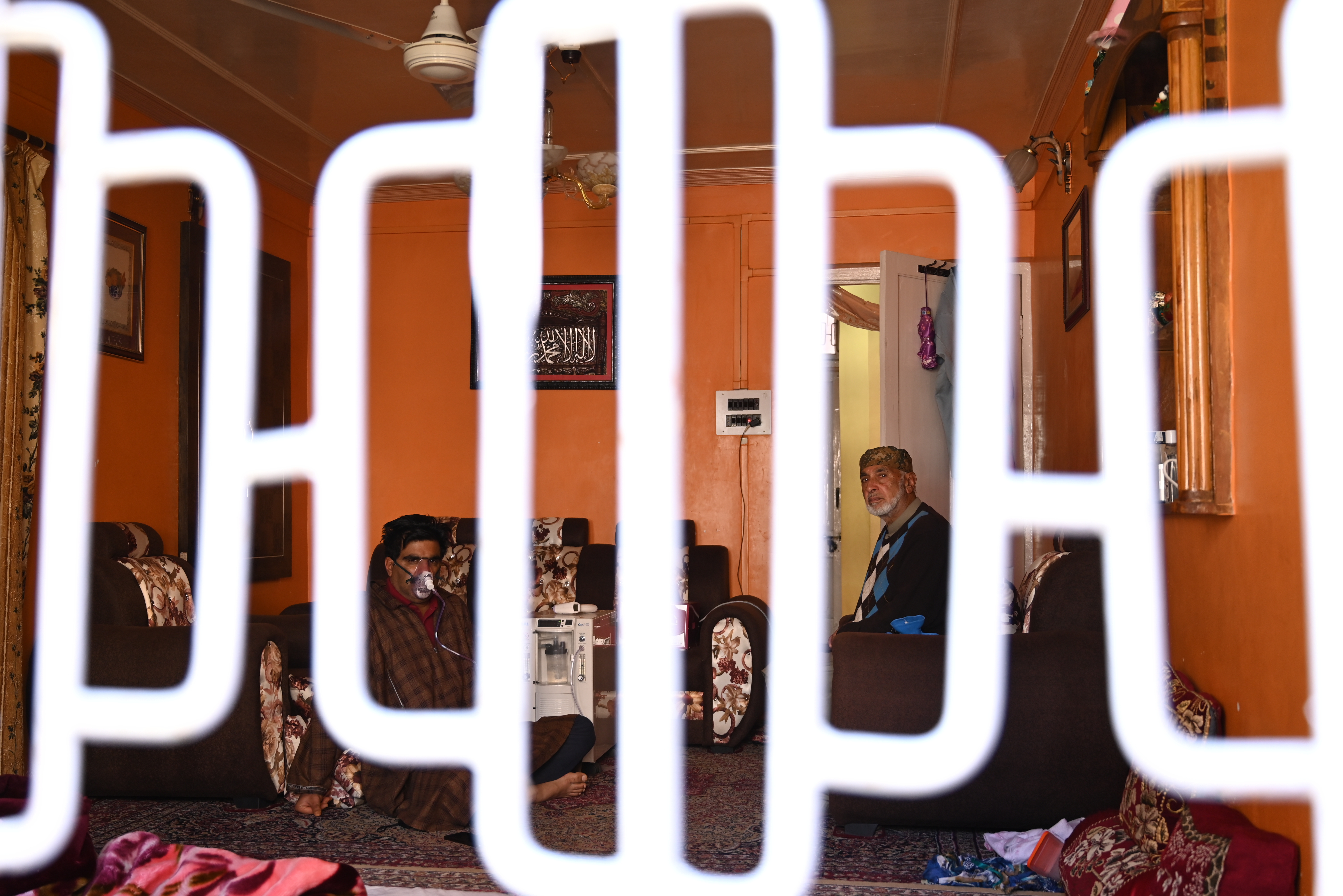 A COVID-positive family in Srinagar, Kashmir, is seen through the window isolating and taking oxygen [Nawal Ali/Al Jazeera]