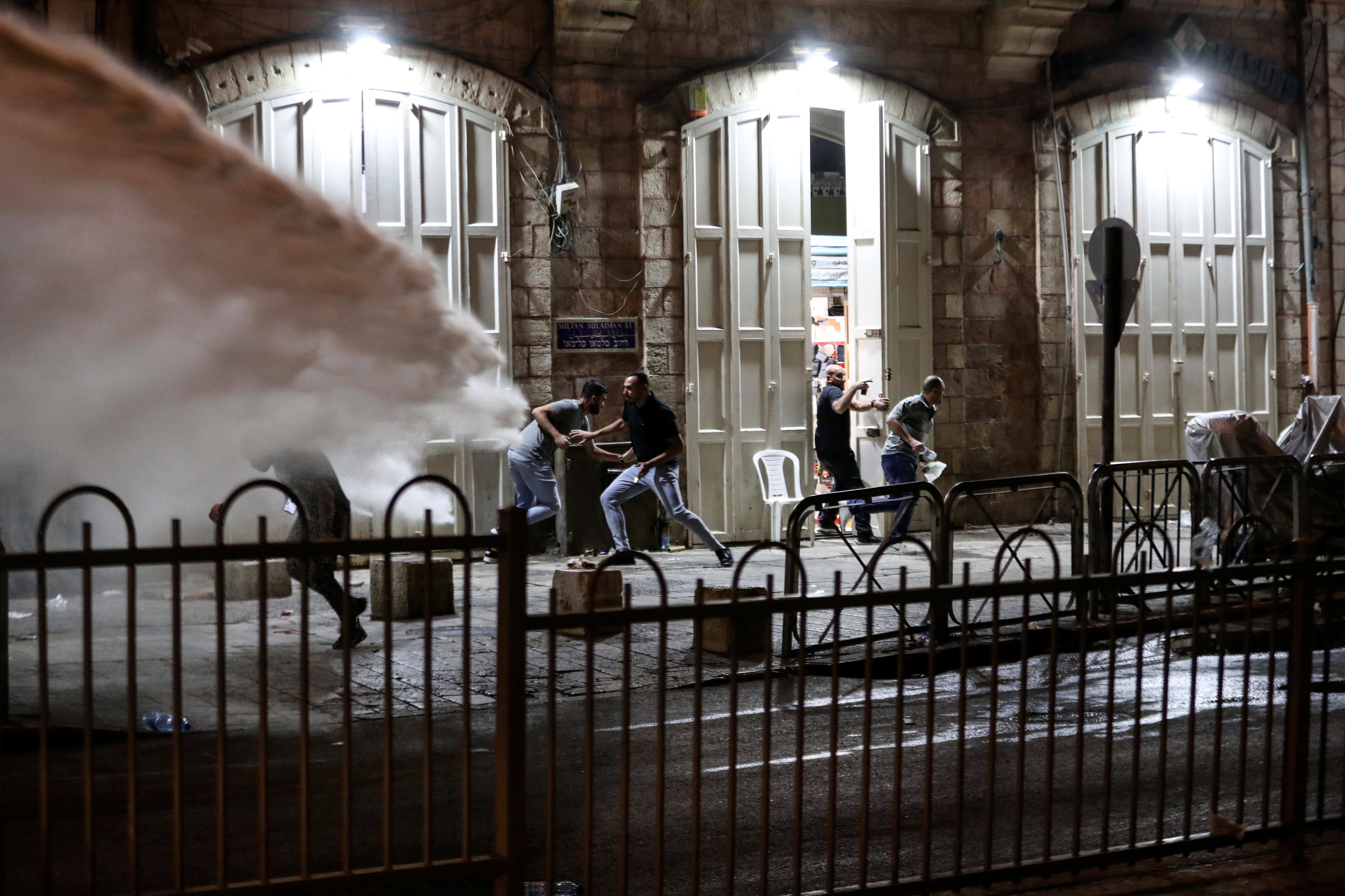 Palestinians run away as Israeli police use a water cannon in Jerusalem’s Old City on May 9