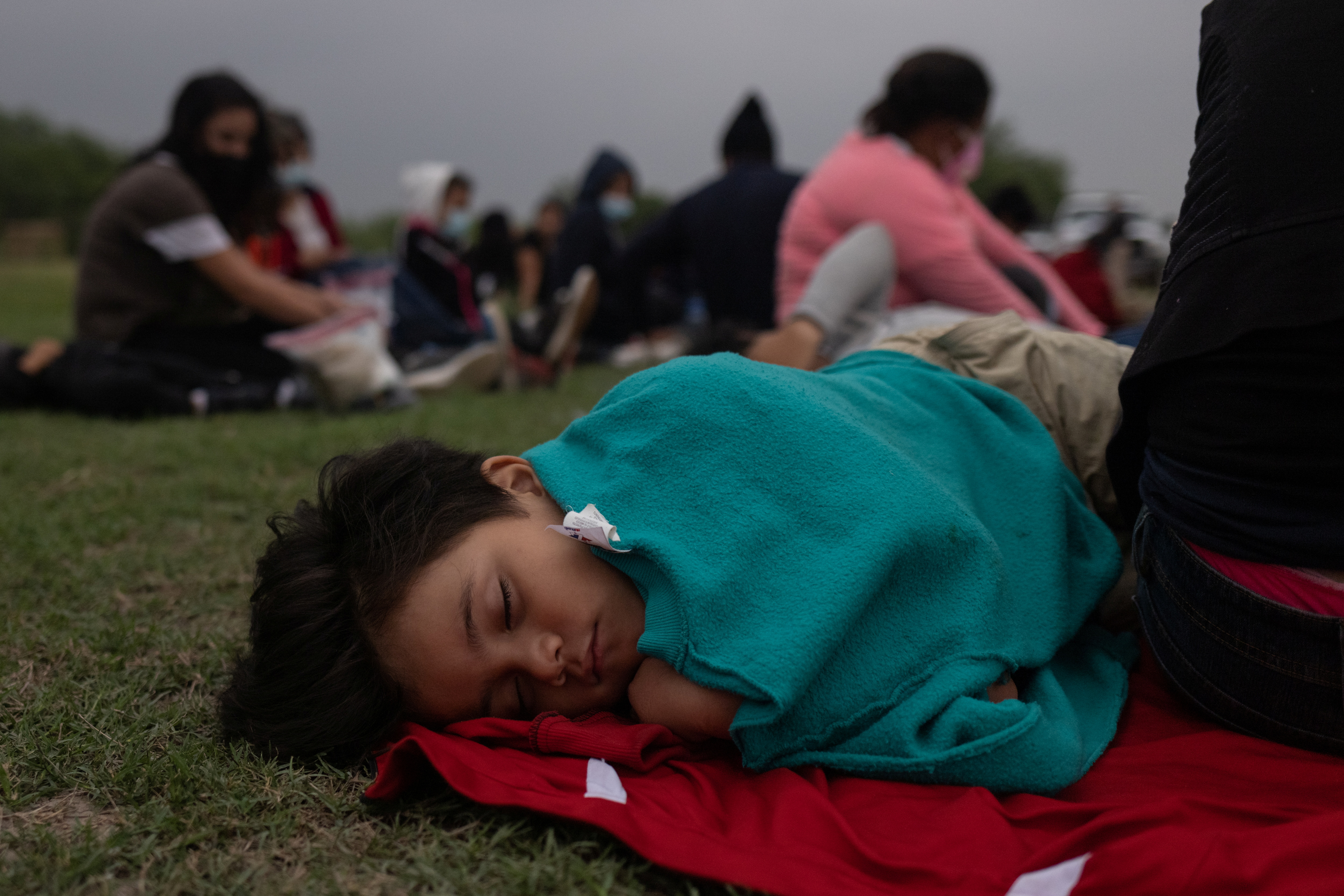 Nathan, a six-year-old boy from Honduras, sleeps next to his mother as they wait with others to be processed by US border patrol agents in La Joya, Texas, on May 19