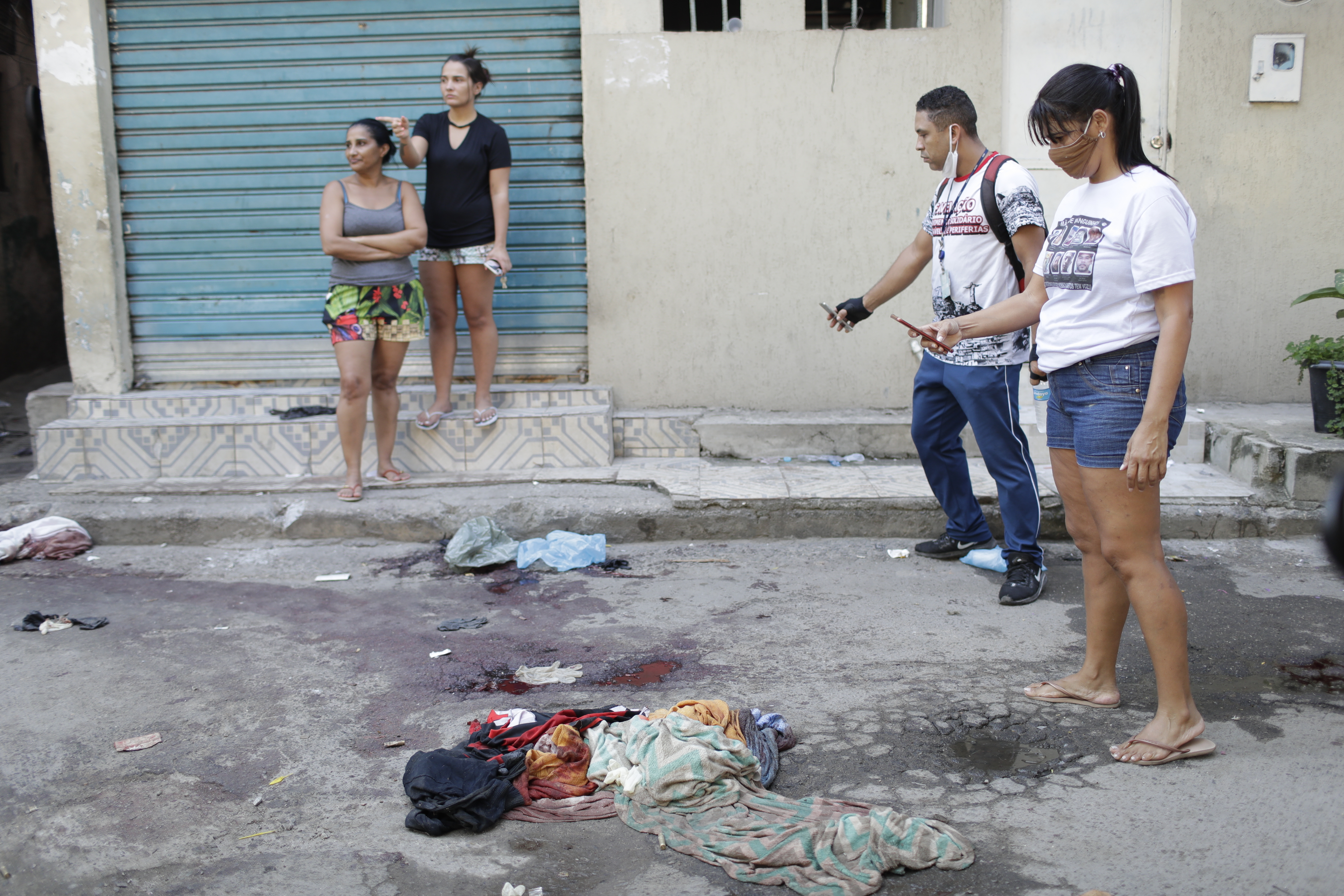Residents take pictures of blood on the street after the police operation in Jacarezinho