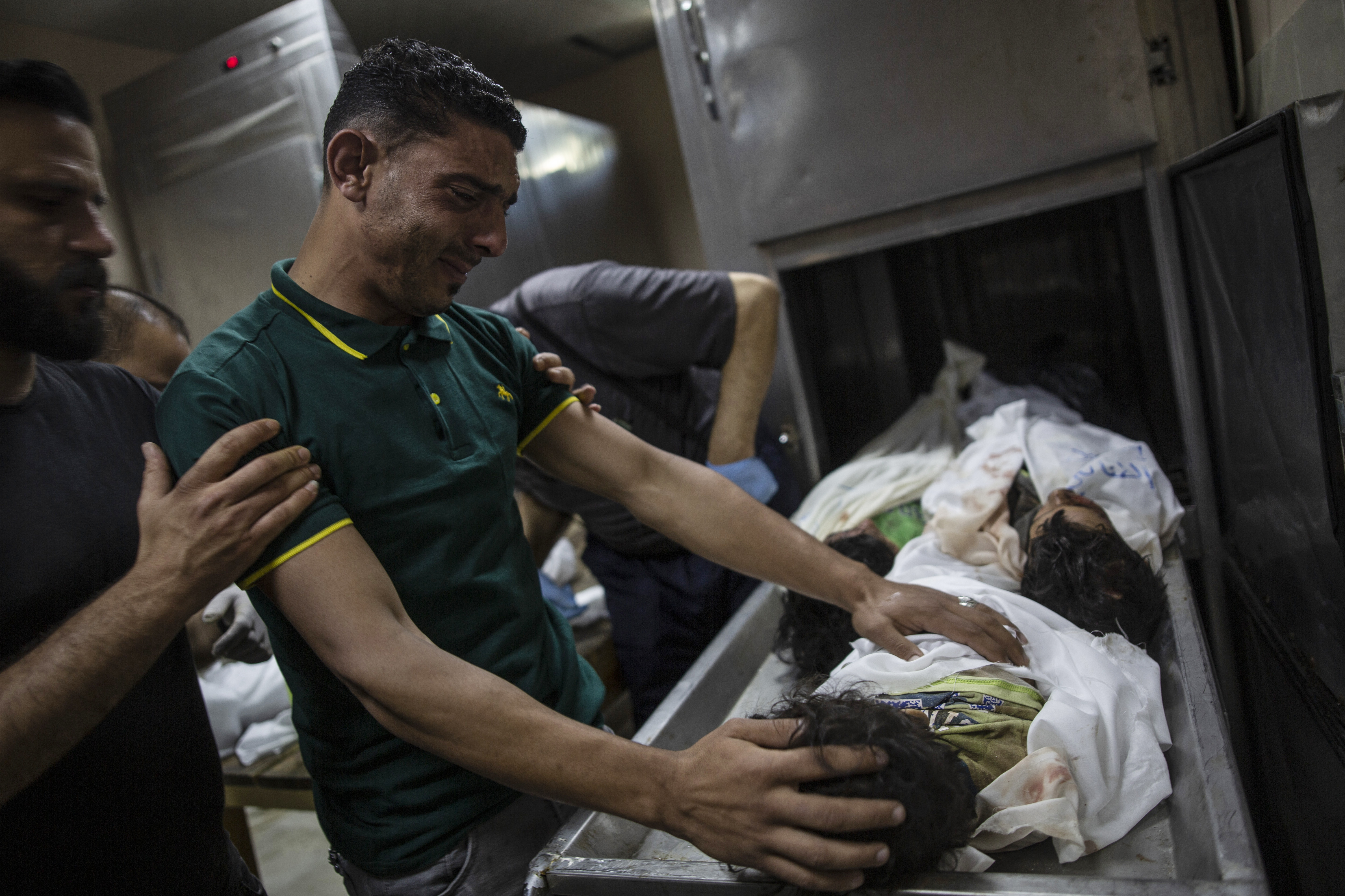 A Palestinian relative mourns over the bodies of four young brothers from the Al-Tanani family who were found under the rubble of a destroyed house following Israeli air raids in Beit Lahiya, northern Gaza Strip, on Friday