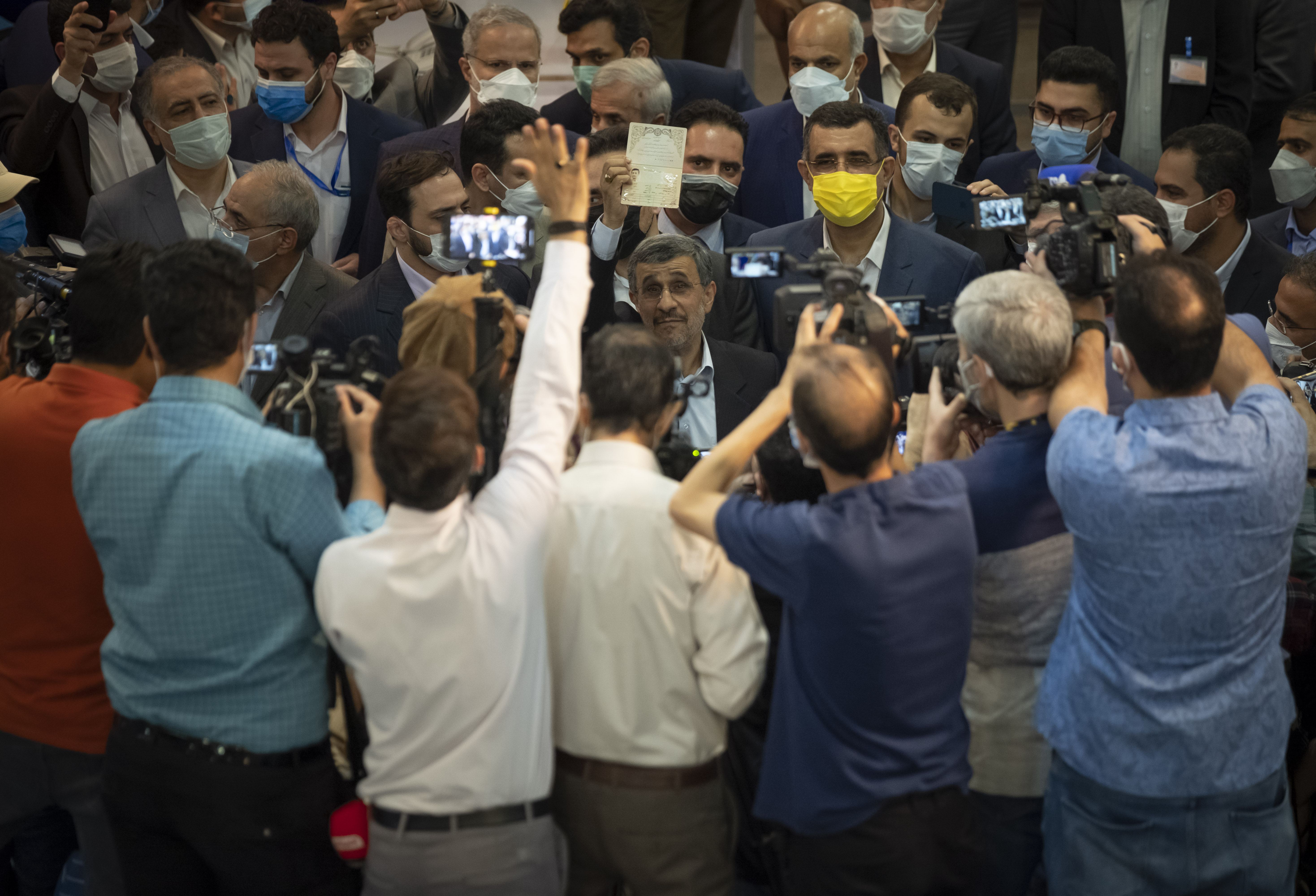 Former president Mahmoud Ahmadinejad (C) holds-up his Identification at the interior ministry, where he registered as a candidate for the June 18 election