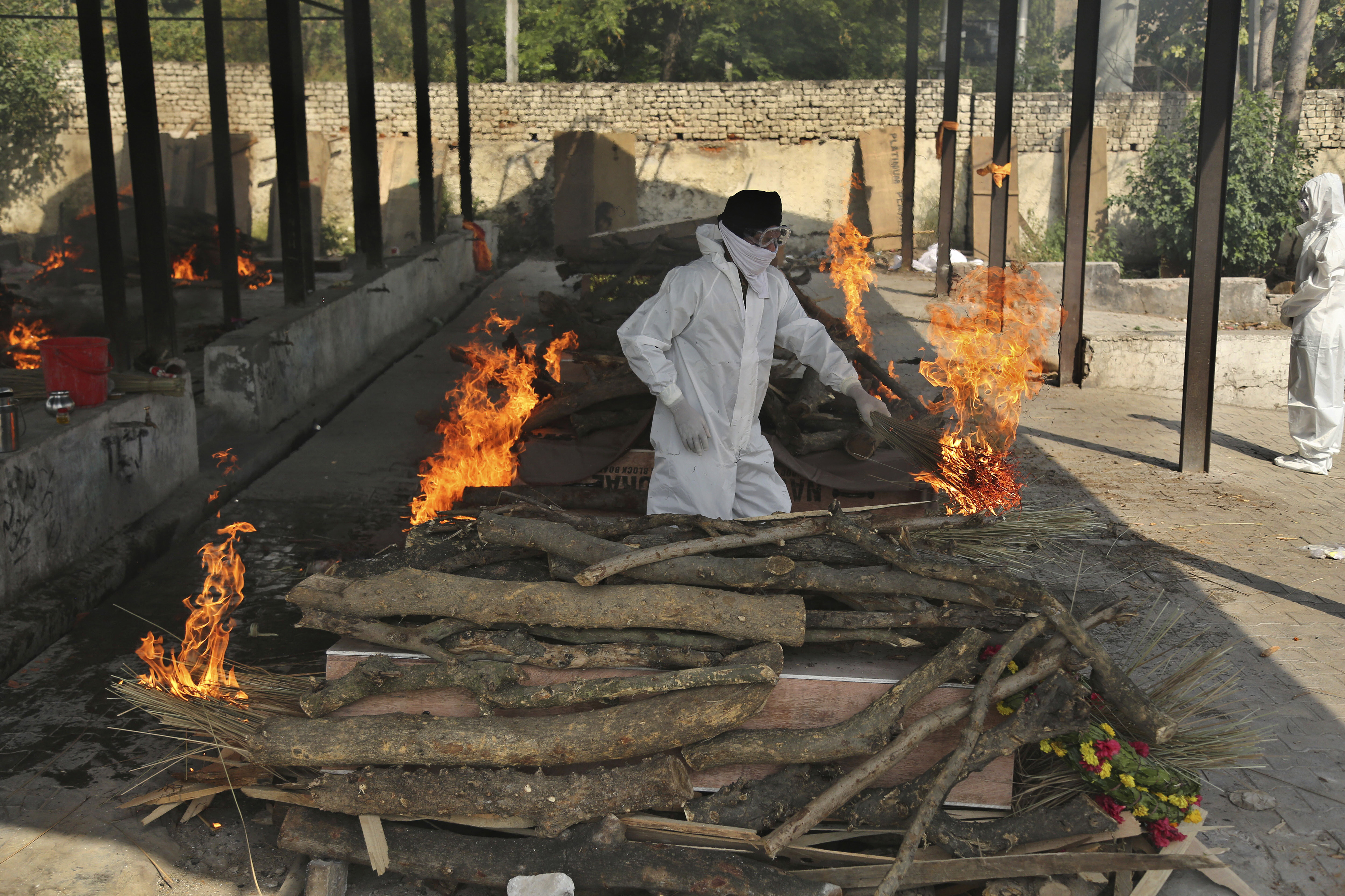 A family member performs the last rites of a COVID-19 victim at a crematorium in Jammu, India, on Friday
