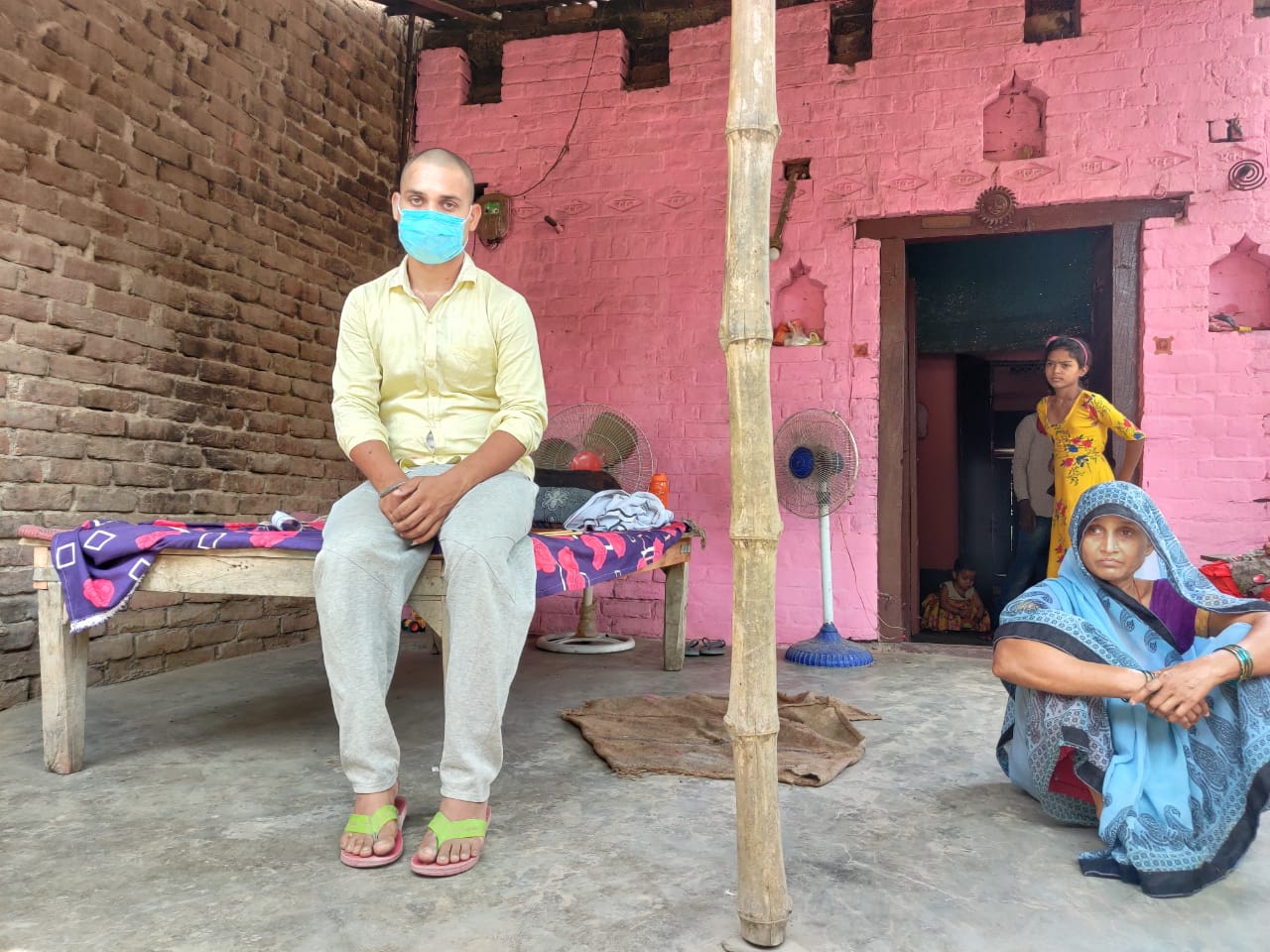 Indrajeet Sahu and his mother outside their house in the village