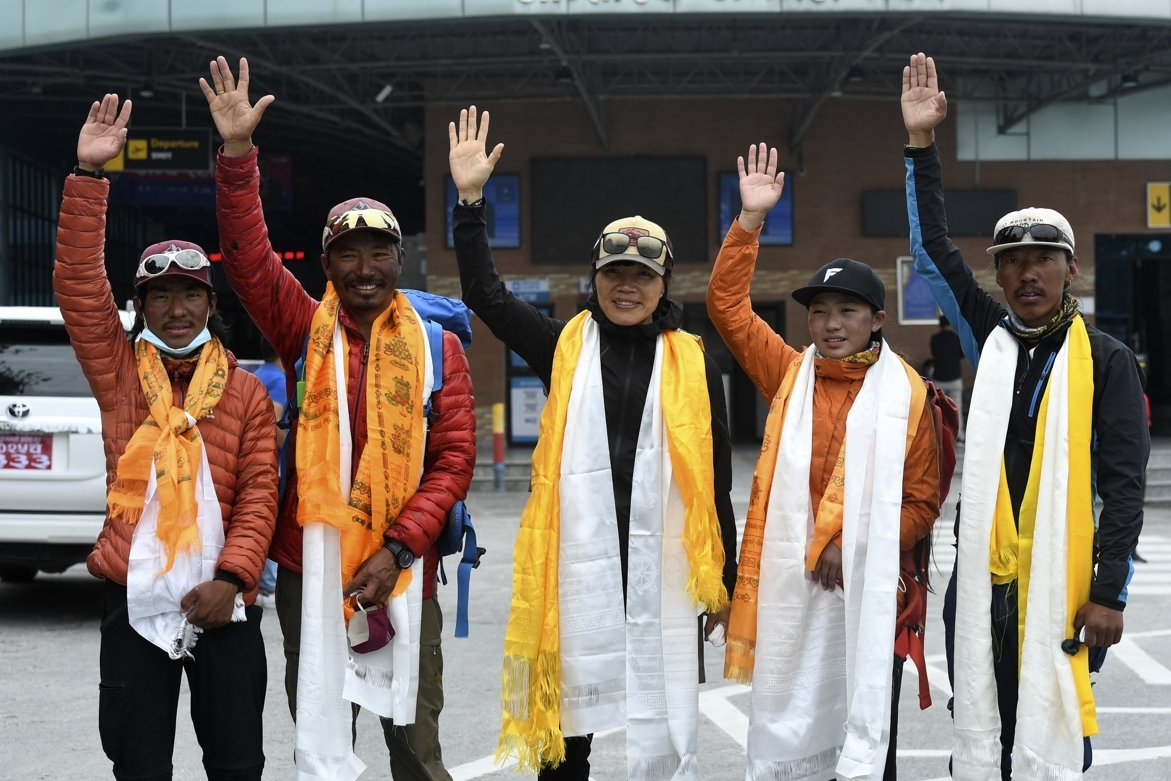 Hong Kong mountaineer Tsang Yin-hung (centre), who climbed Everest in a record 25 hours and 50 minutes, waves alongside mountaineers Pemba Dorje Sherpa (second left), Phurba Thiley Sherpa (left), Nima Lhamu Sherpa (second right) and Phurba Tenjing Sherpa (right) as they arrive back at the airport in Kathmandu