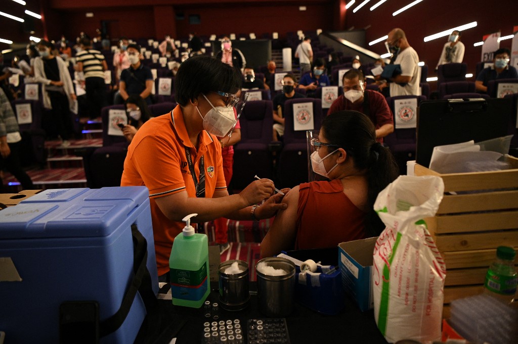 A health worker administers a Chinese Sinovac vaccine against COVI-19 coronavirus disease to a resident inside a movie theatre turned into a vaccination centre in suburban Manila earlier this month