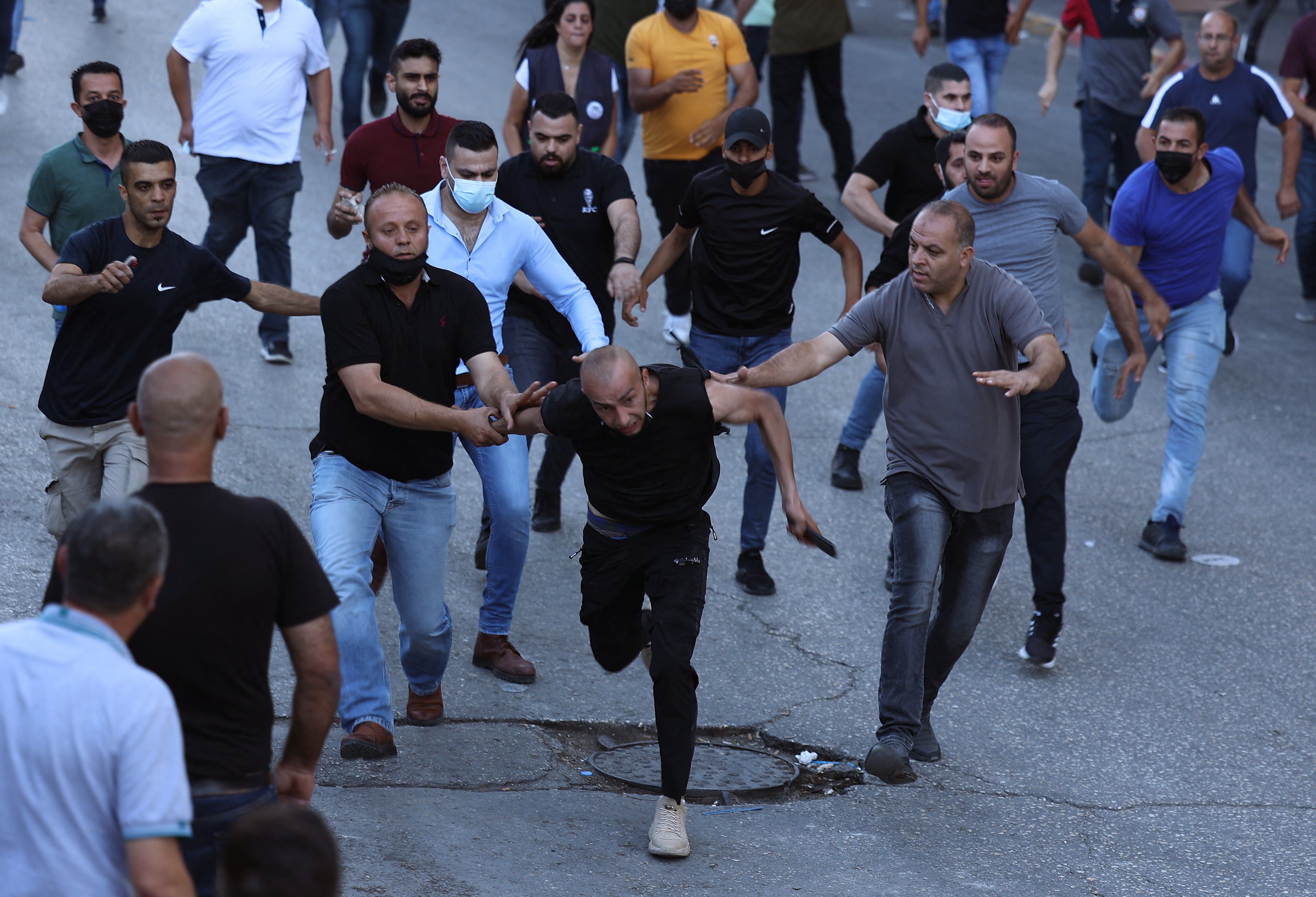 Palestinian plain-clothed security officers detain a protester in the occupied West Bank city of Ramallah