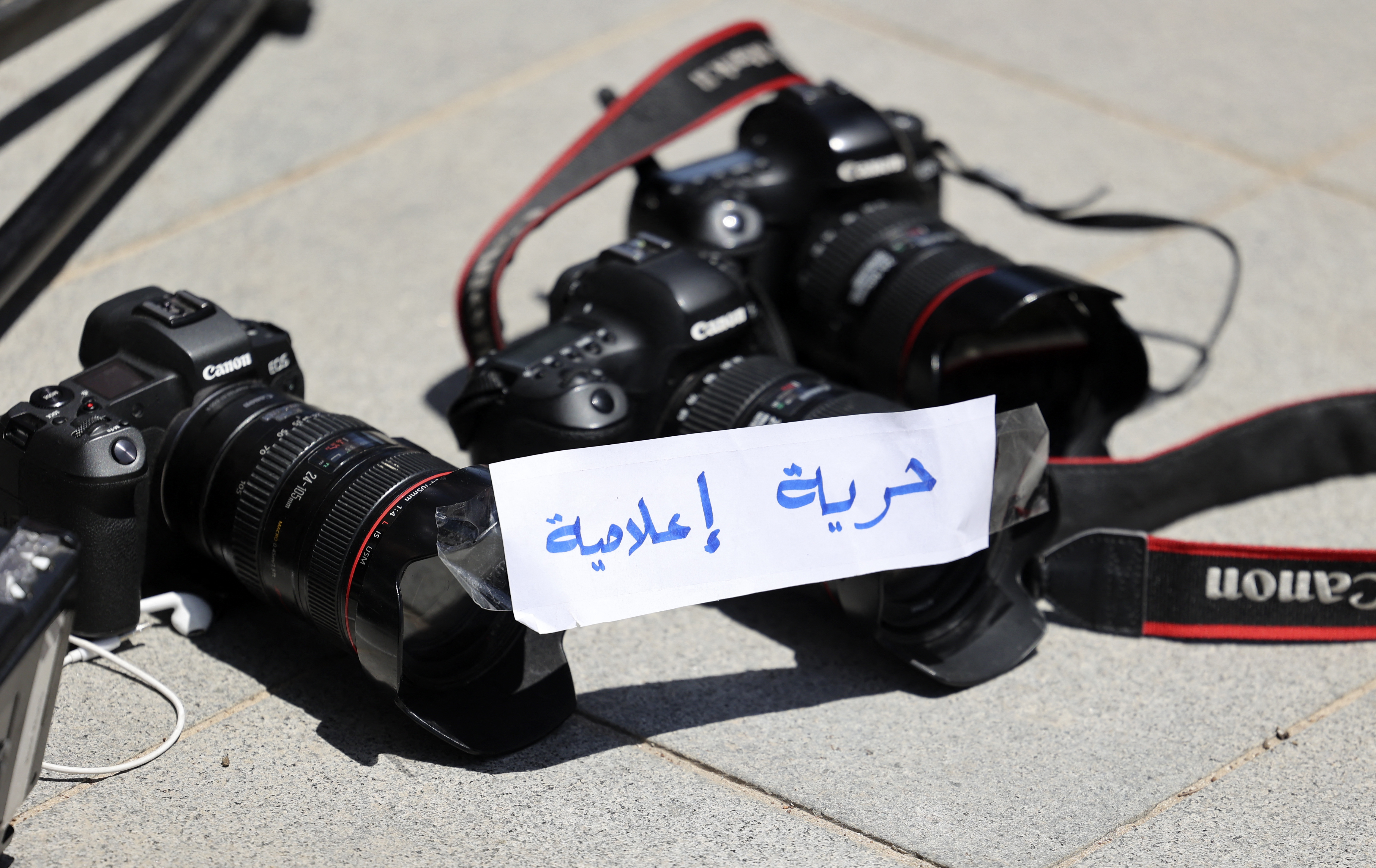 Photojournalists leave their cameras on the ground with a note reading in Arabic ‘Freedom of Press’ during a protest outside the UN office in the occupied West Bank city of Ramallah