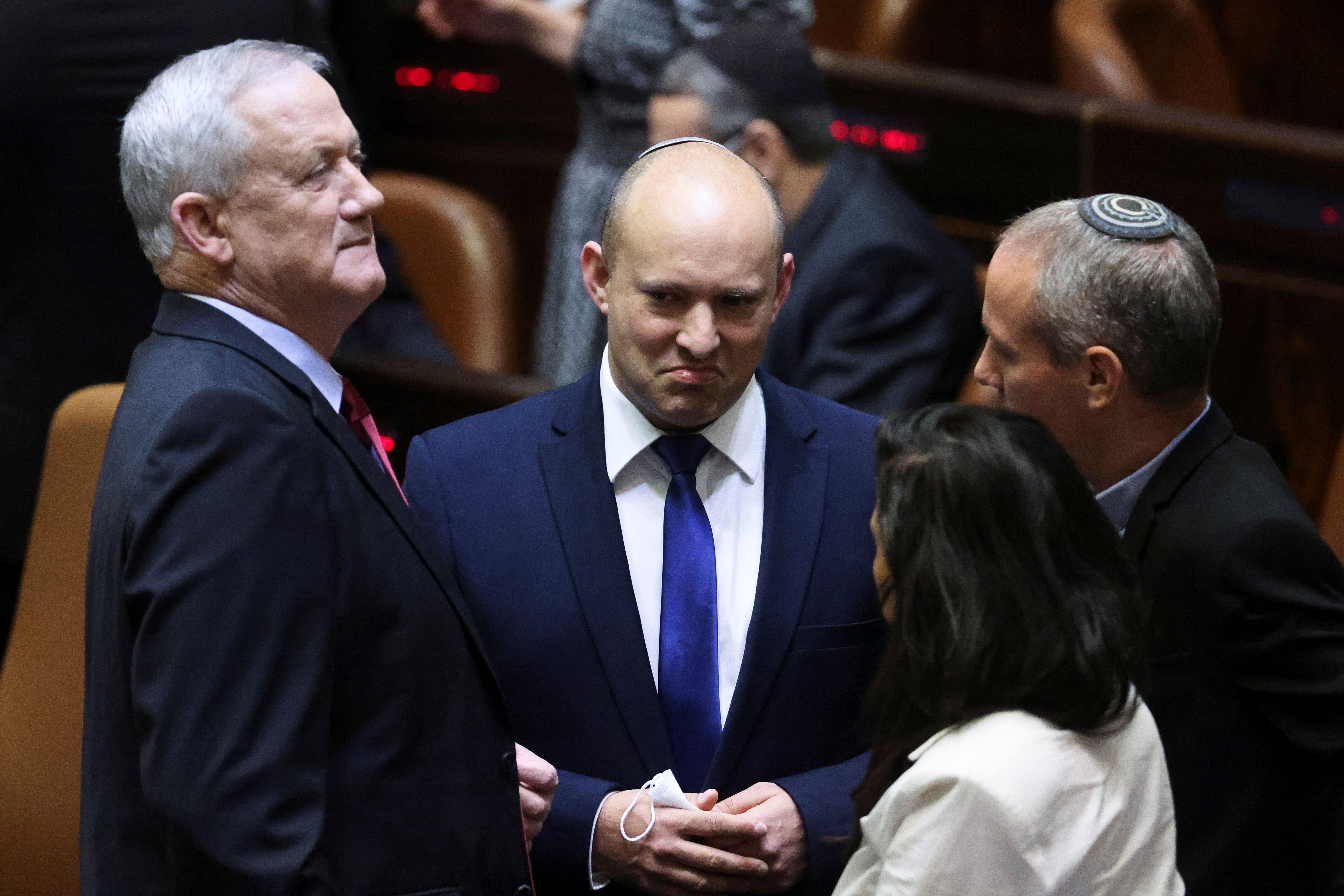 Defence Minister and leader of Blue and White party Benny Gantz, left, speaks to Yamina leader Naftali Bennett, (centre), during a special session of the Knesset at the plenum in Jerusalem