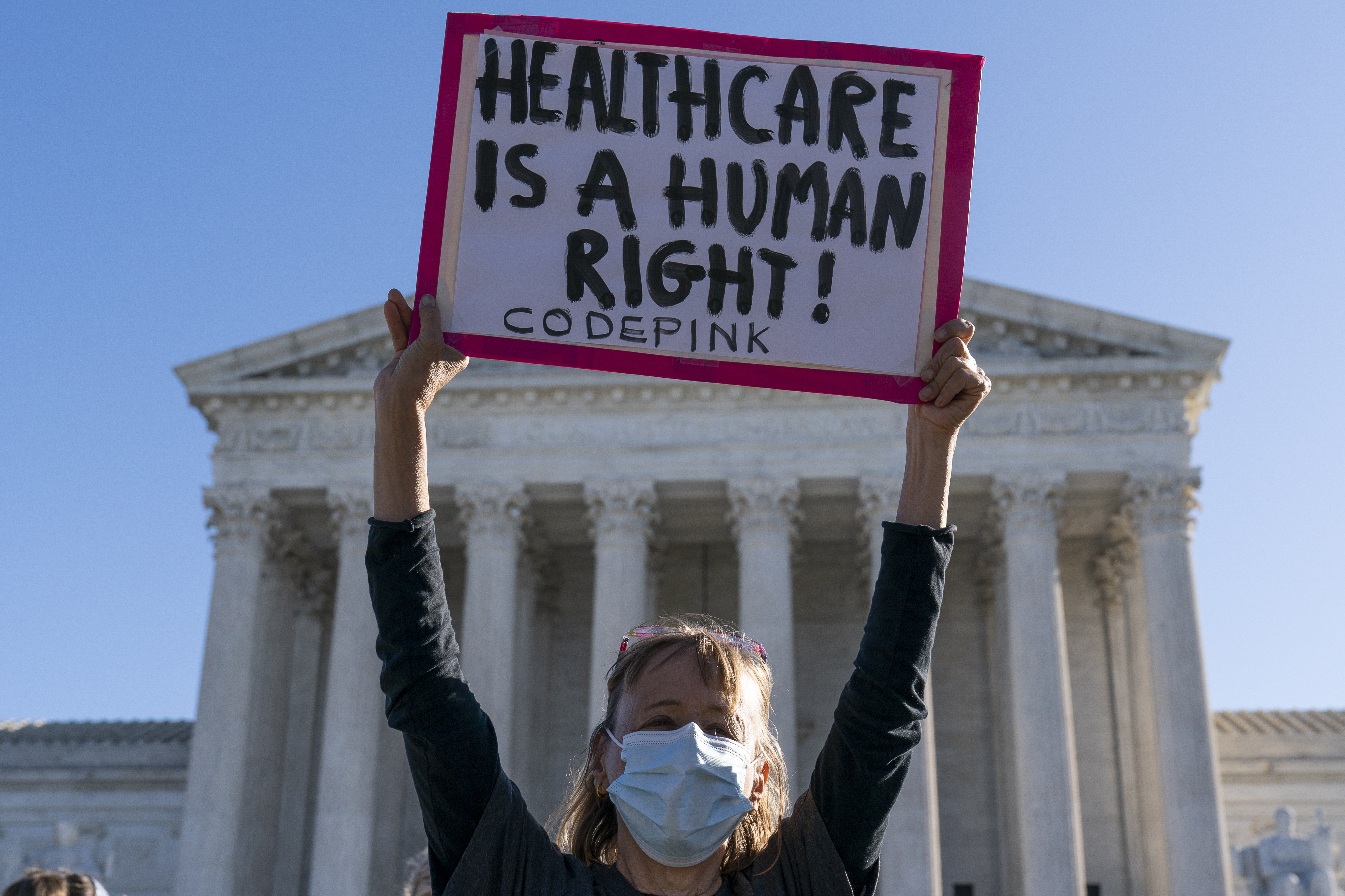 A demonstrator holding a sign in front of the US Supreme Court during arguments about the Affordable Care Act on Tuesday