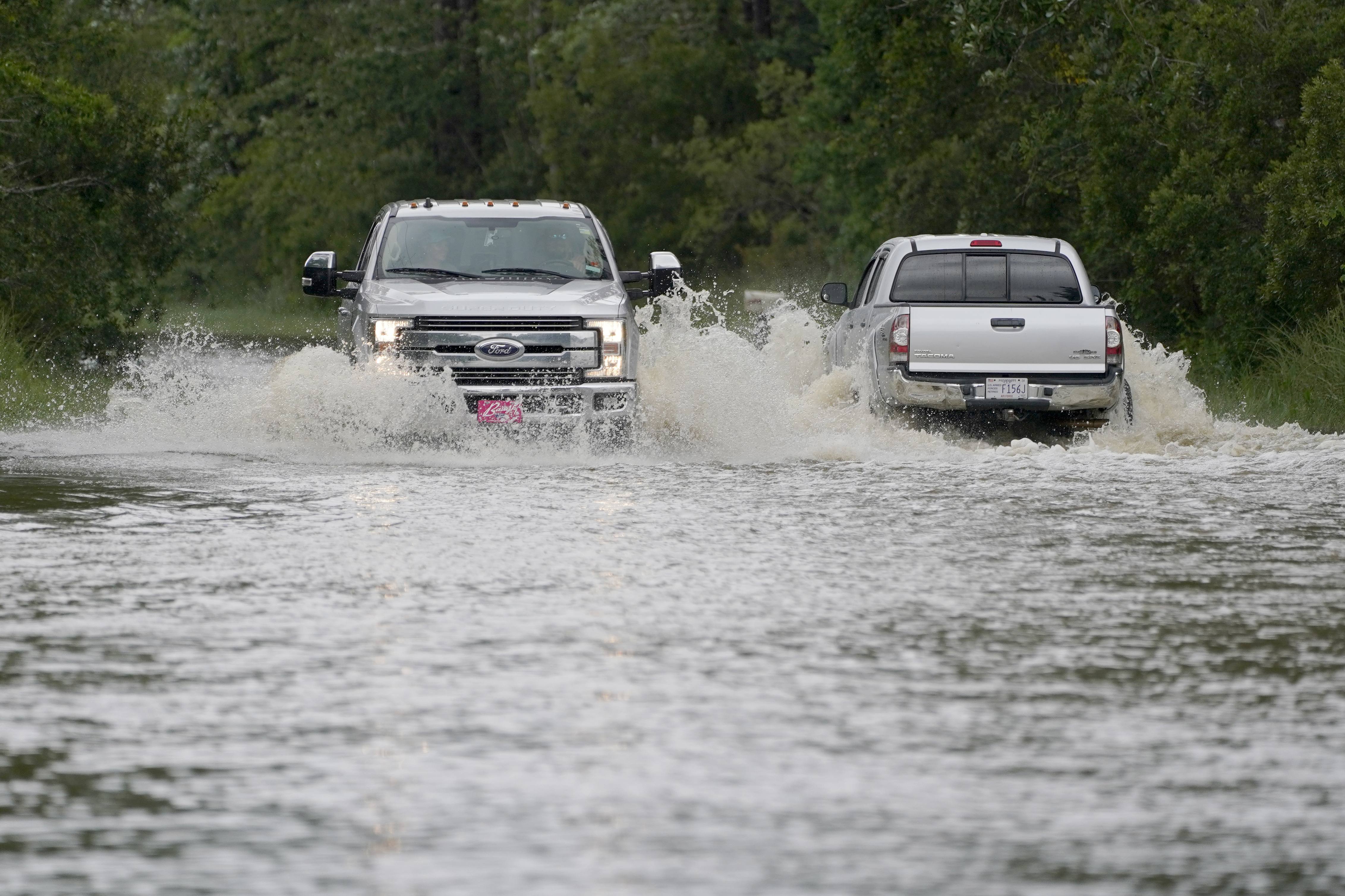 Pickup trucks pass each other on the flooded Cedar Lake Road in Biloxi, Mississippi