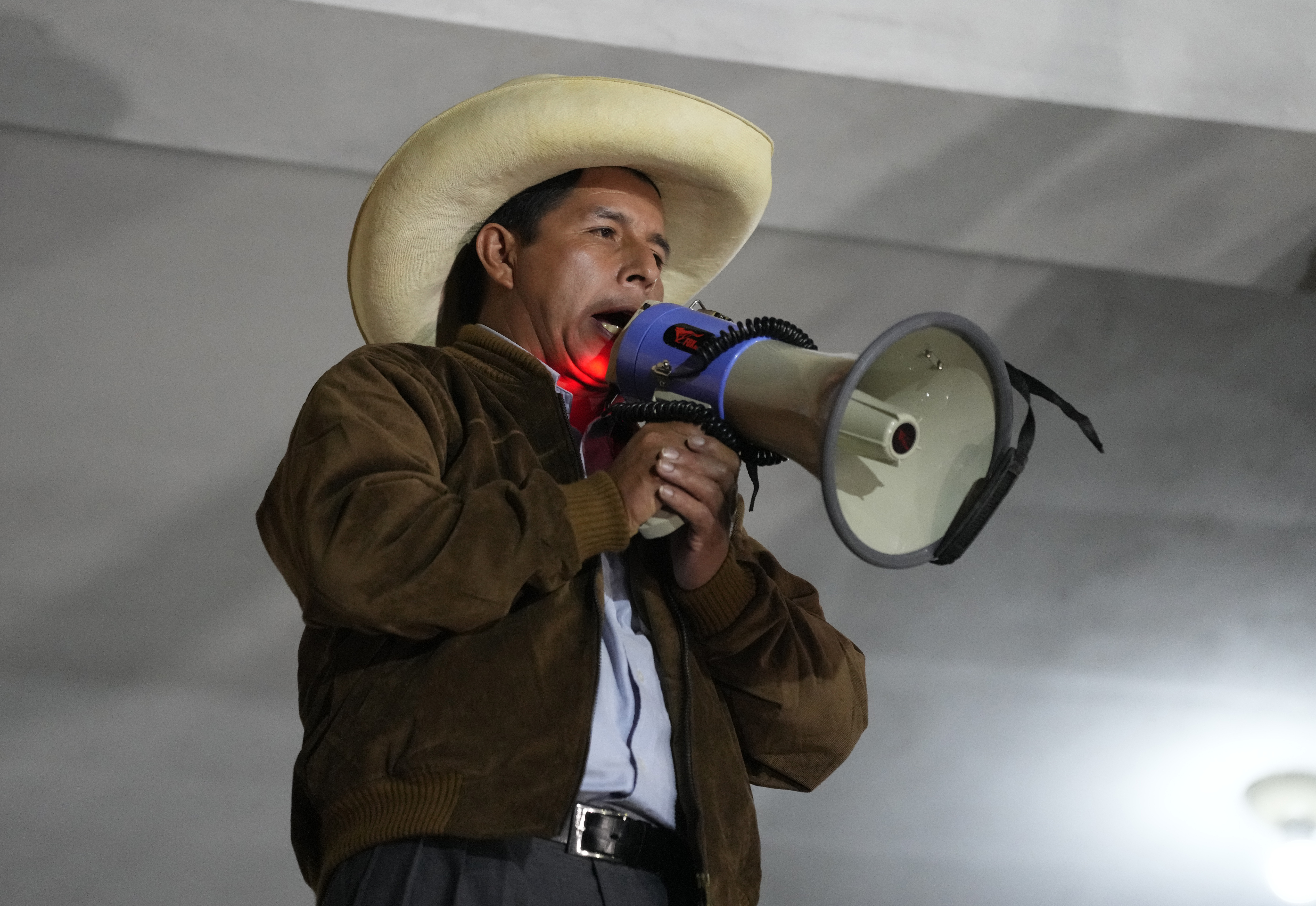 Presidential candidate Pedro Castillo uses a bullhorn to speak to his supporters, from a balcony of his party headquarters during a runoff election, in Tacabamba, Peru, Sunday, June 6, 2021