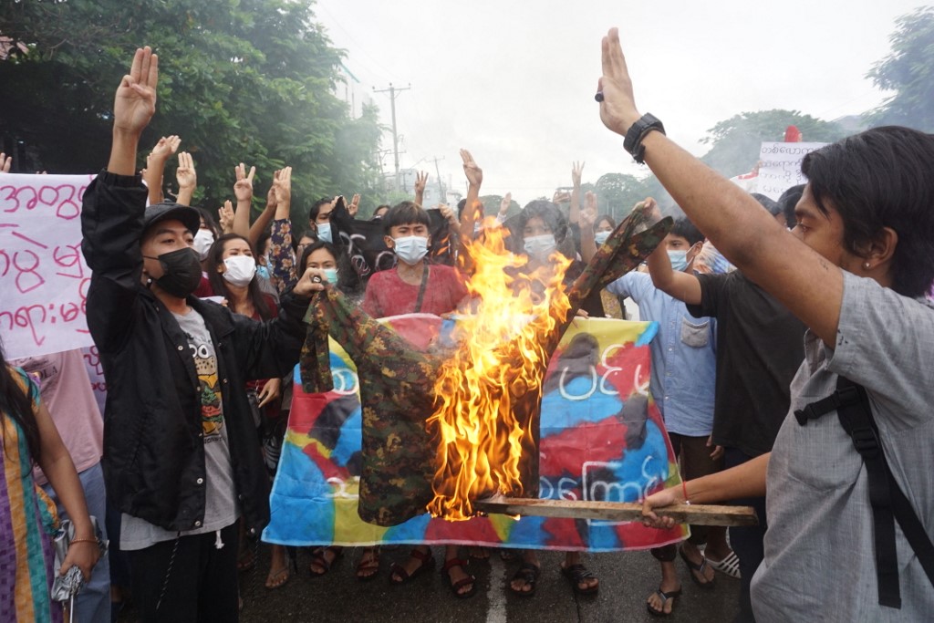 Protesters burn a military uniform as they take part in a flash mob demonstration against the coup in Yangon on July 1 [AFP]