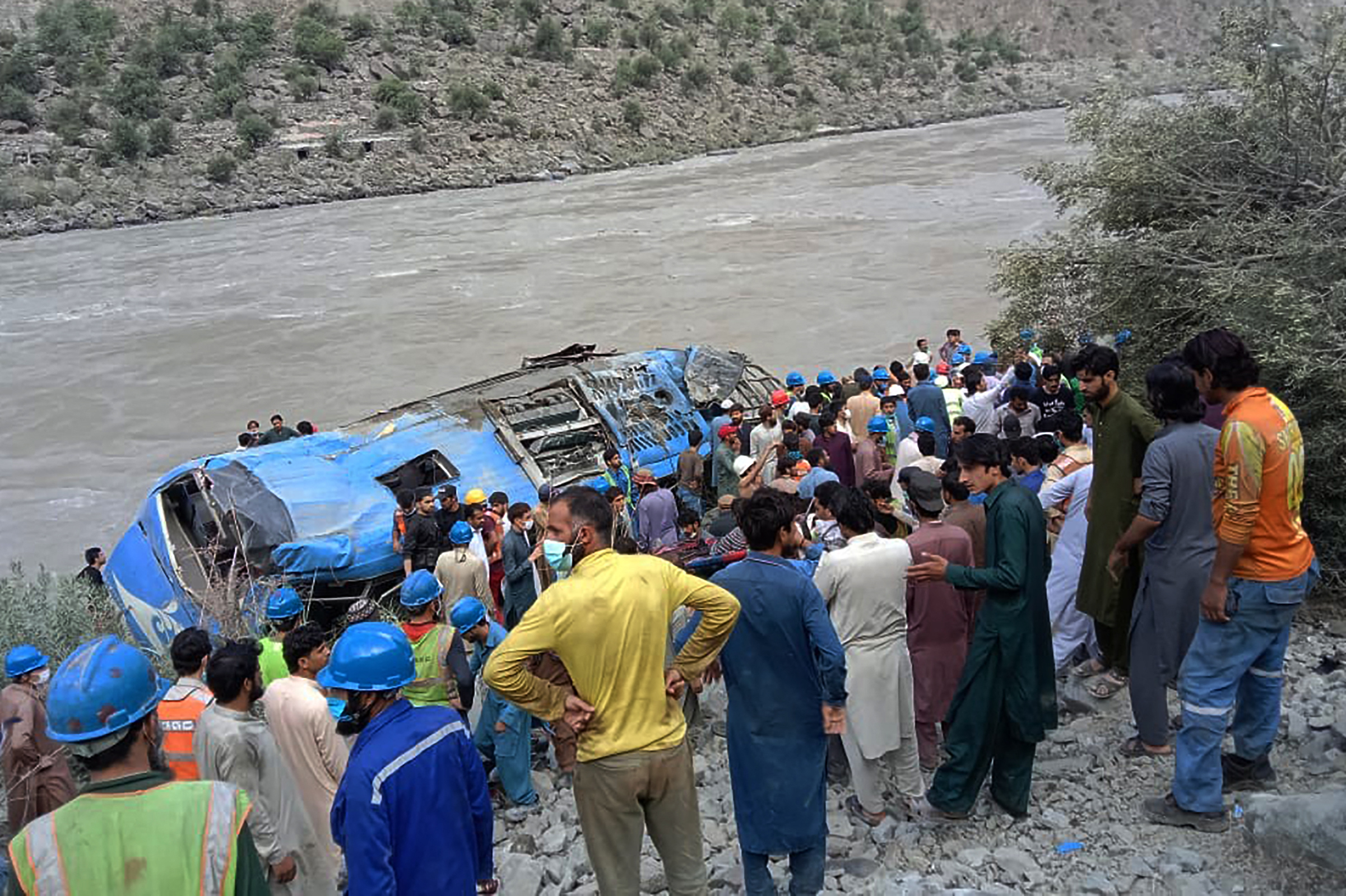 Rescue workers and onlookers gather around a wreck after a bus plunged into a ravine following the bomb explosion
