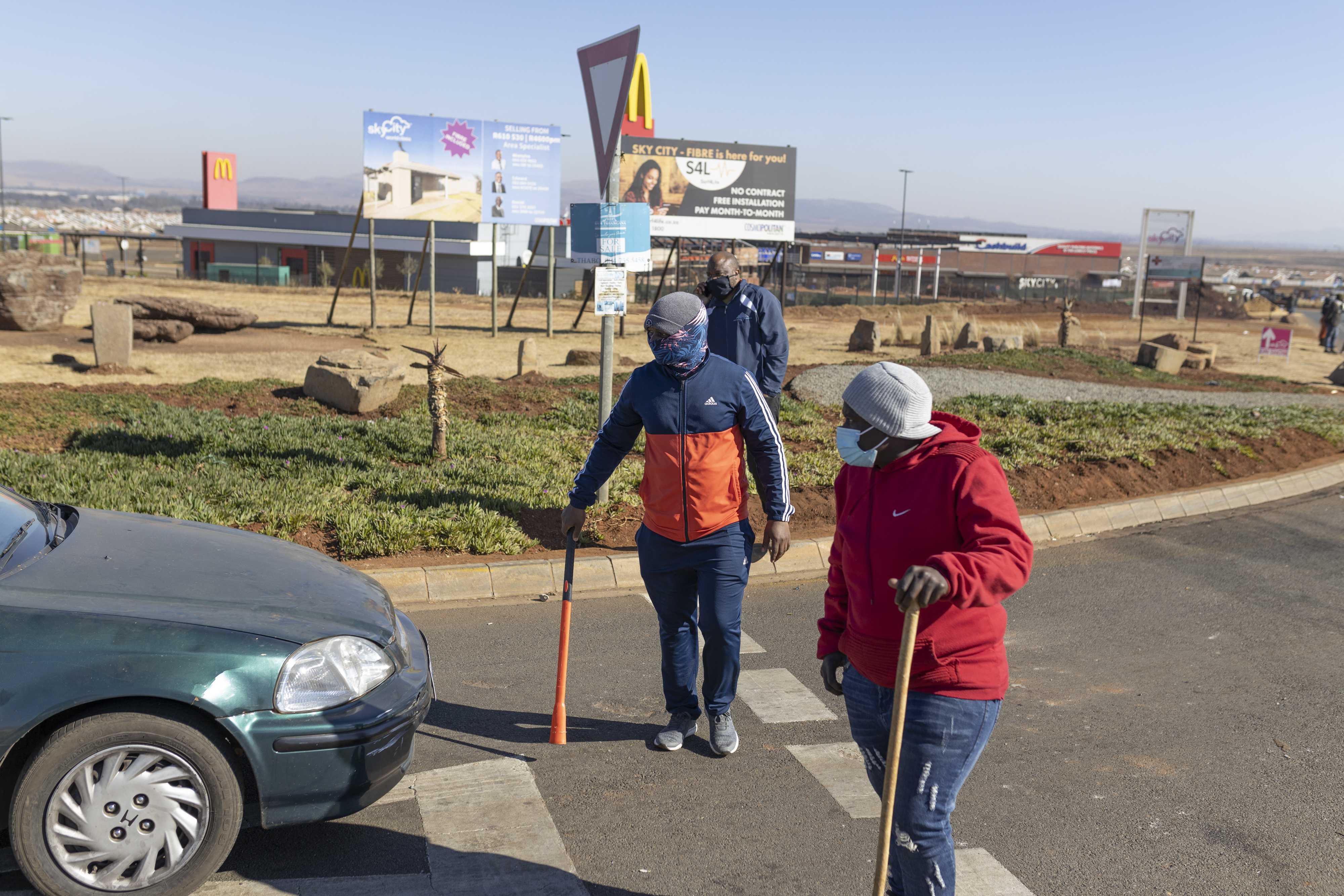 Community members stand on a road to protect the entrance of the Sky City Mall in Vereeniging from possible looting
