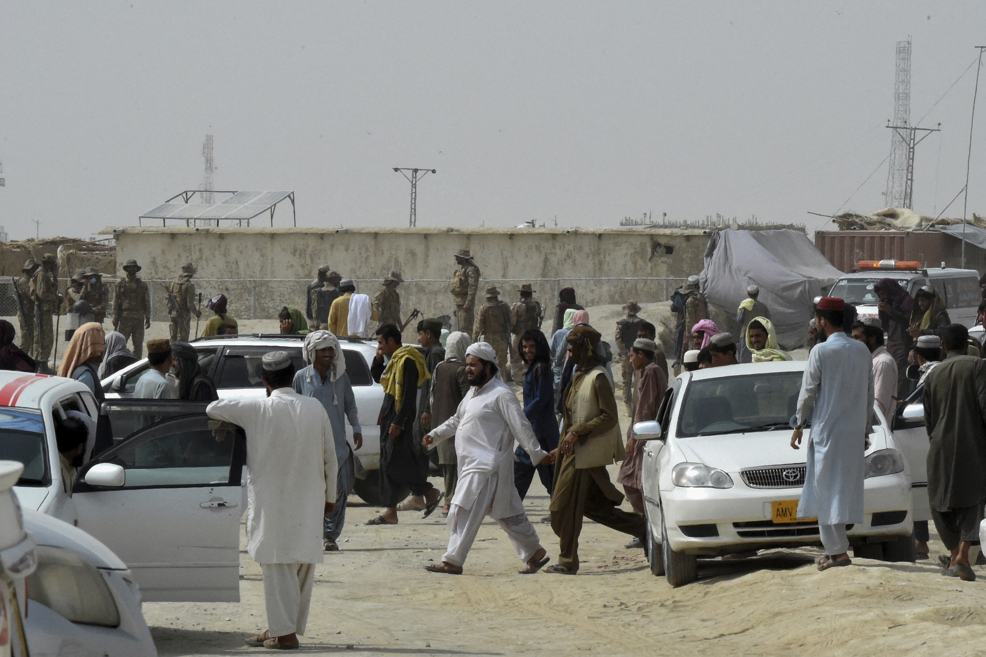 Stranded people gather as Pakistani troops stand guard at the border town of Chaman