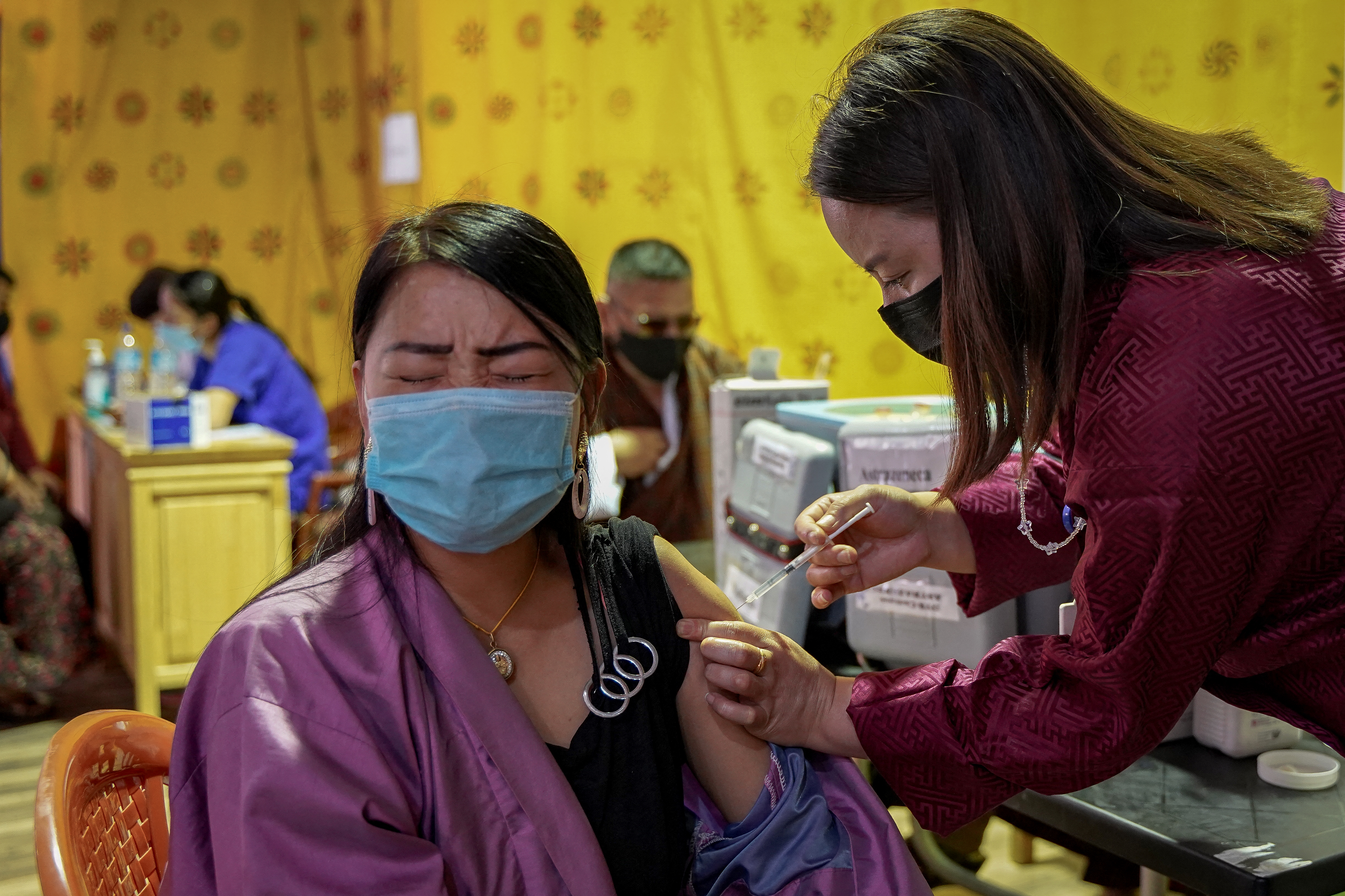 A health worker inoculates a woman with the jab of the COVID-19 coronavirus vaccine at a temporary vaccination centre in Thimphu