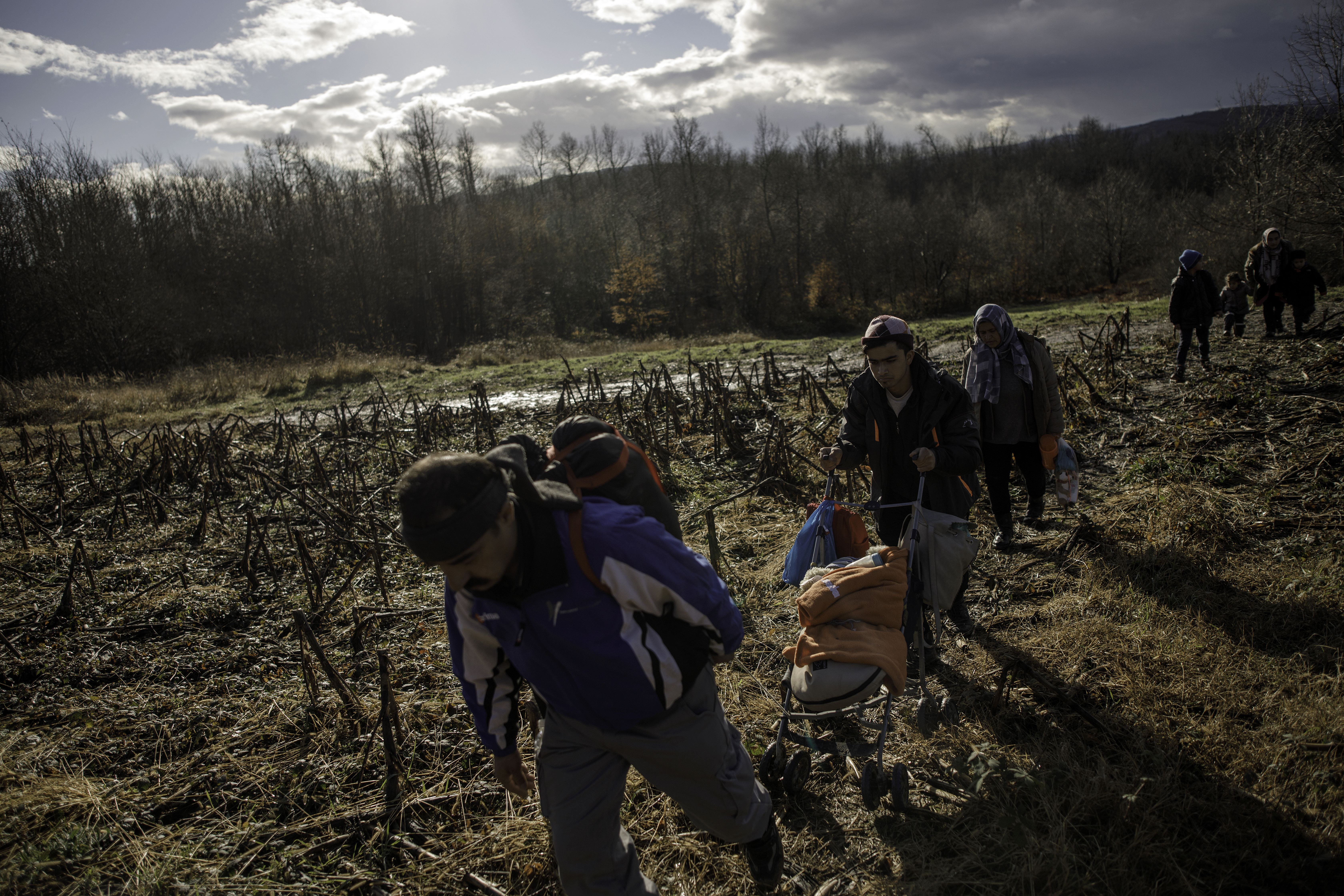 A baby is pushed in a stroller as members of a migrant family from Afghanistan approach Croatia's border from Bosnian side
