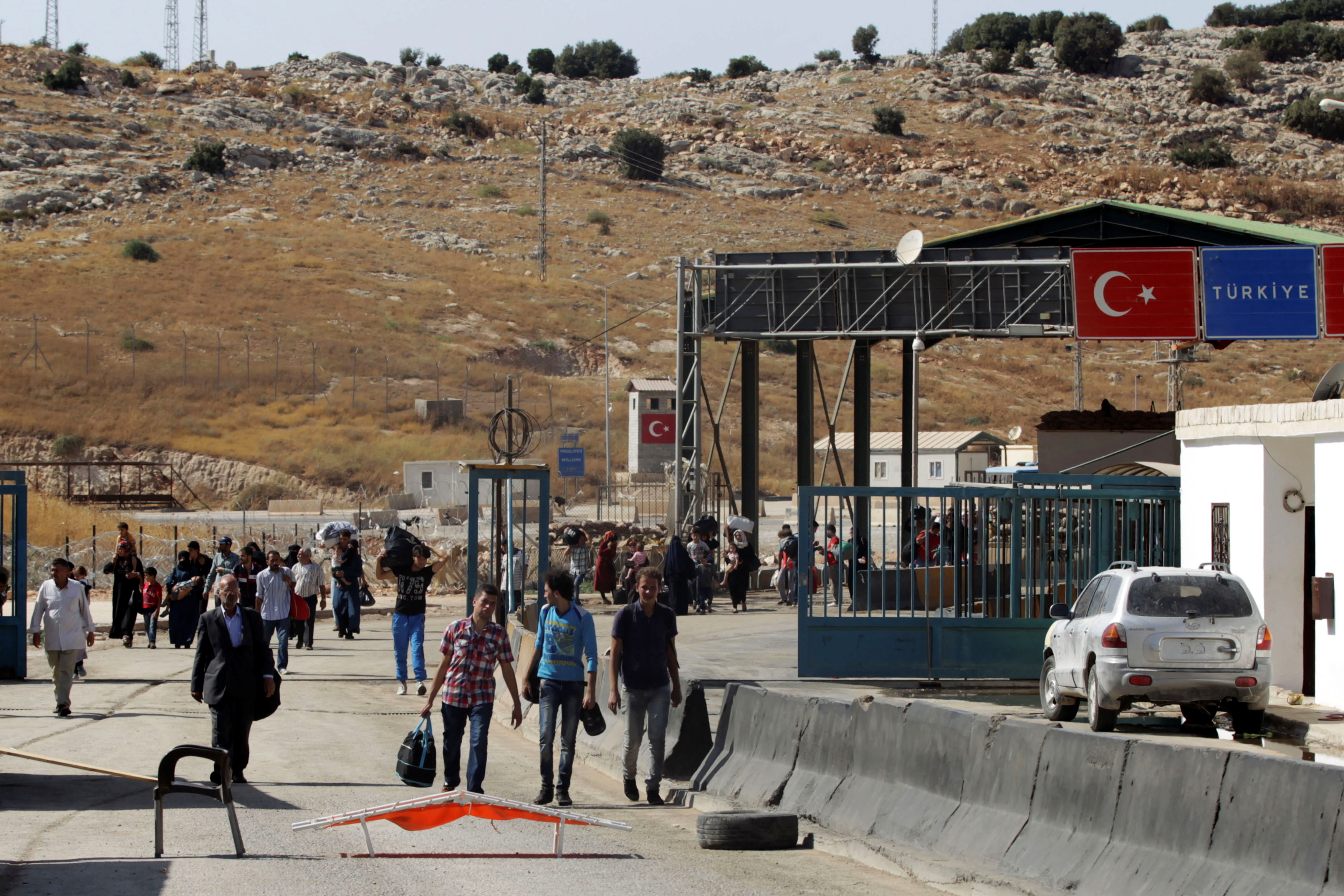 Syrians carry their belongings as they cross back into Syria at the Syrian-Turkish border crossing of Bab al-Hawa in Idlib province