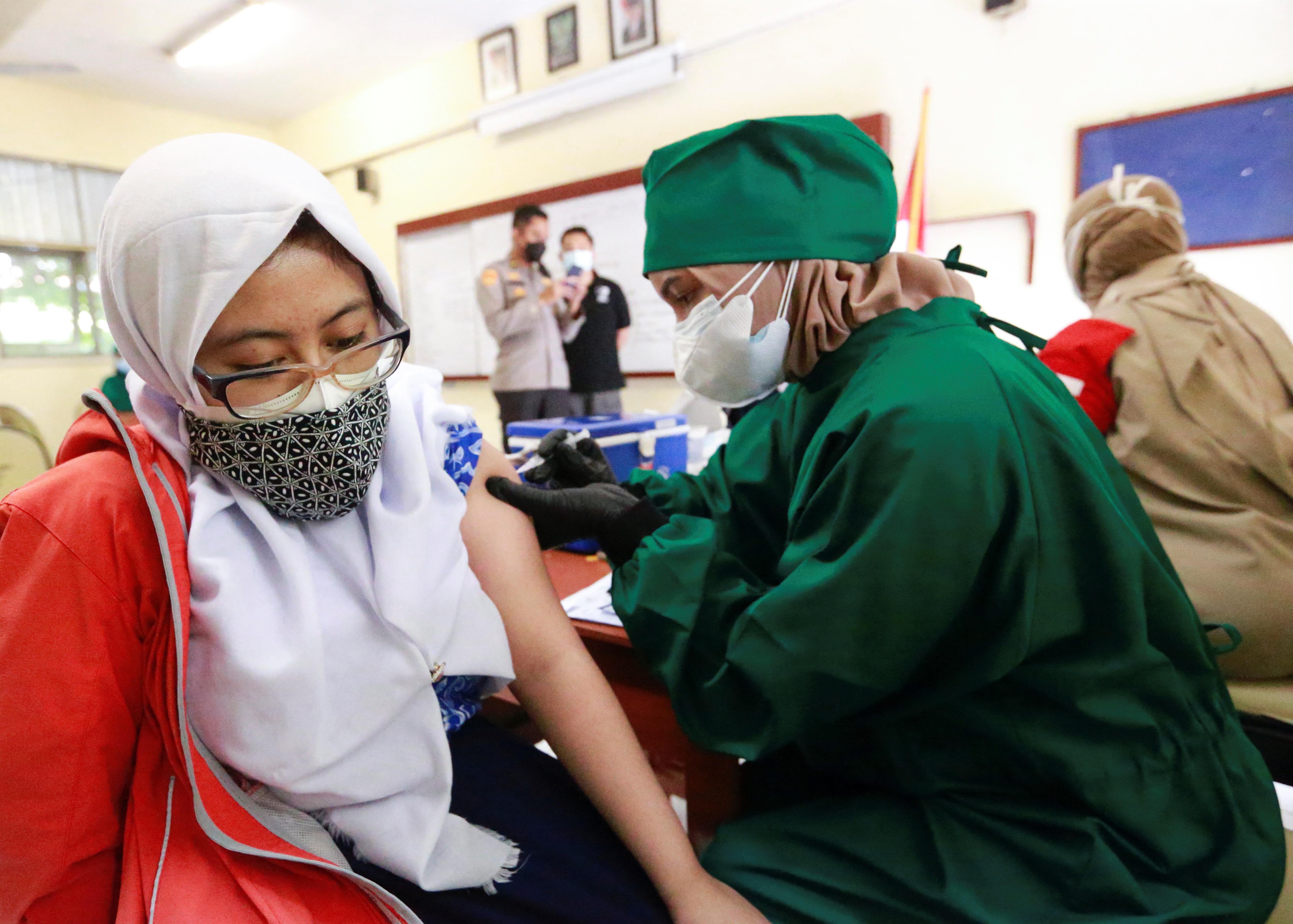 A student receives a dose of the vaccine against the coronavirus disease during a mass vaccination programme for students at a school in Jakarta