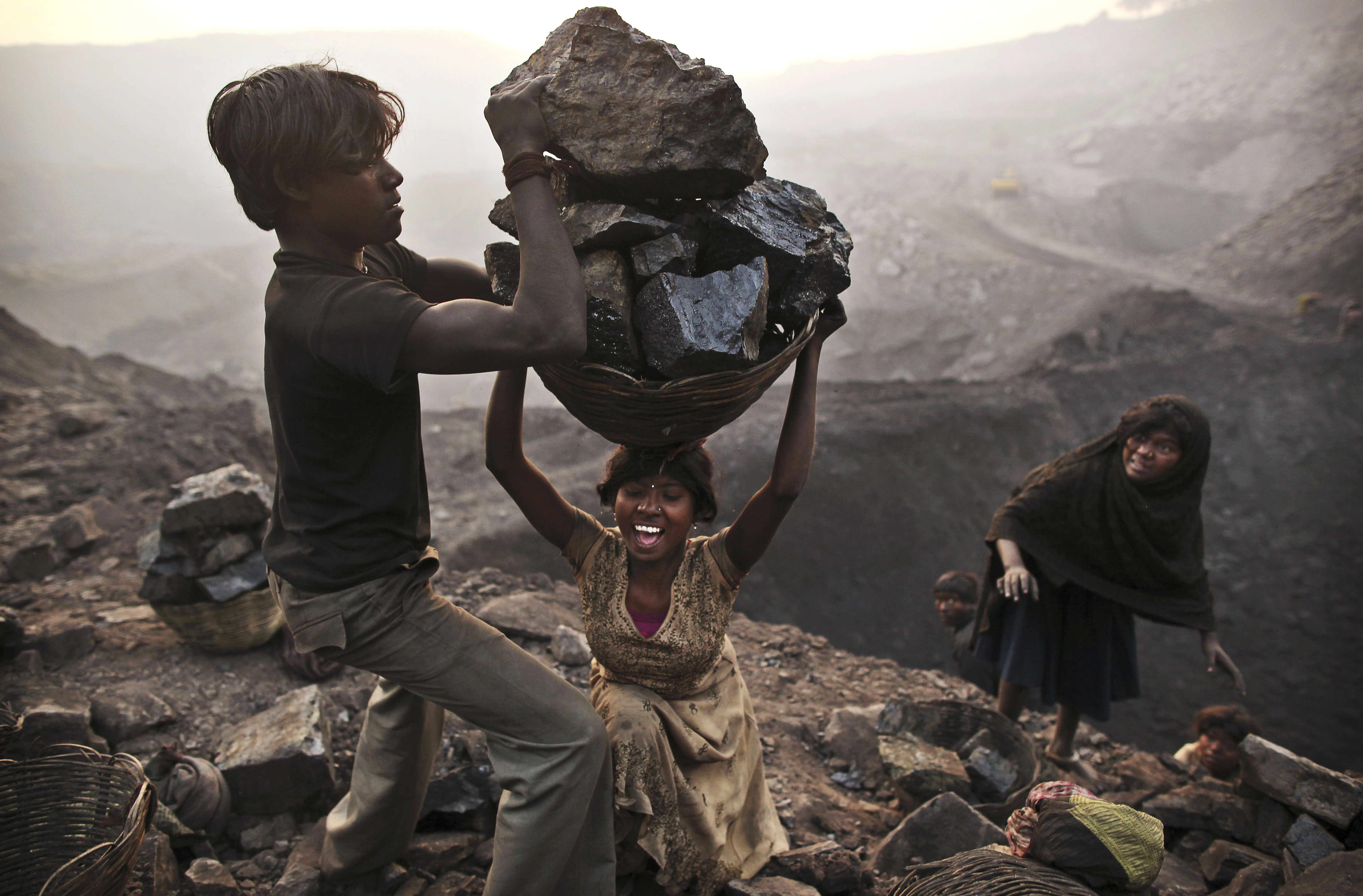 A young woman stumbles as she tries to carry a large basket of coal in the village of Bokapahari in the eastern Indian state of Jharkhand