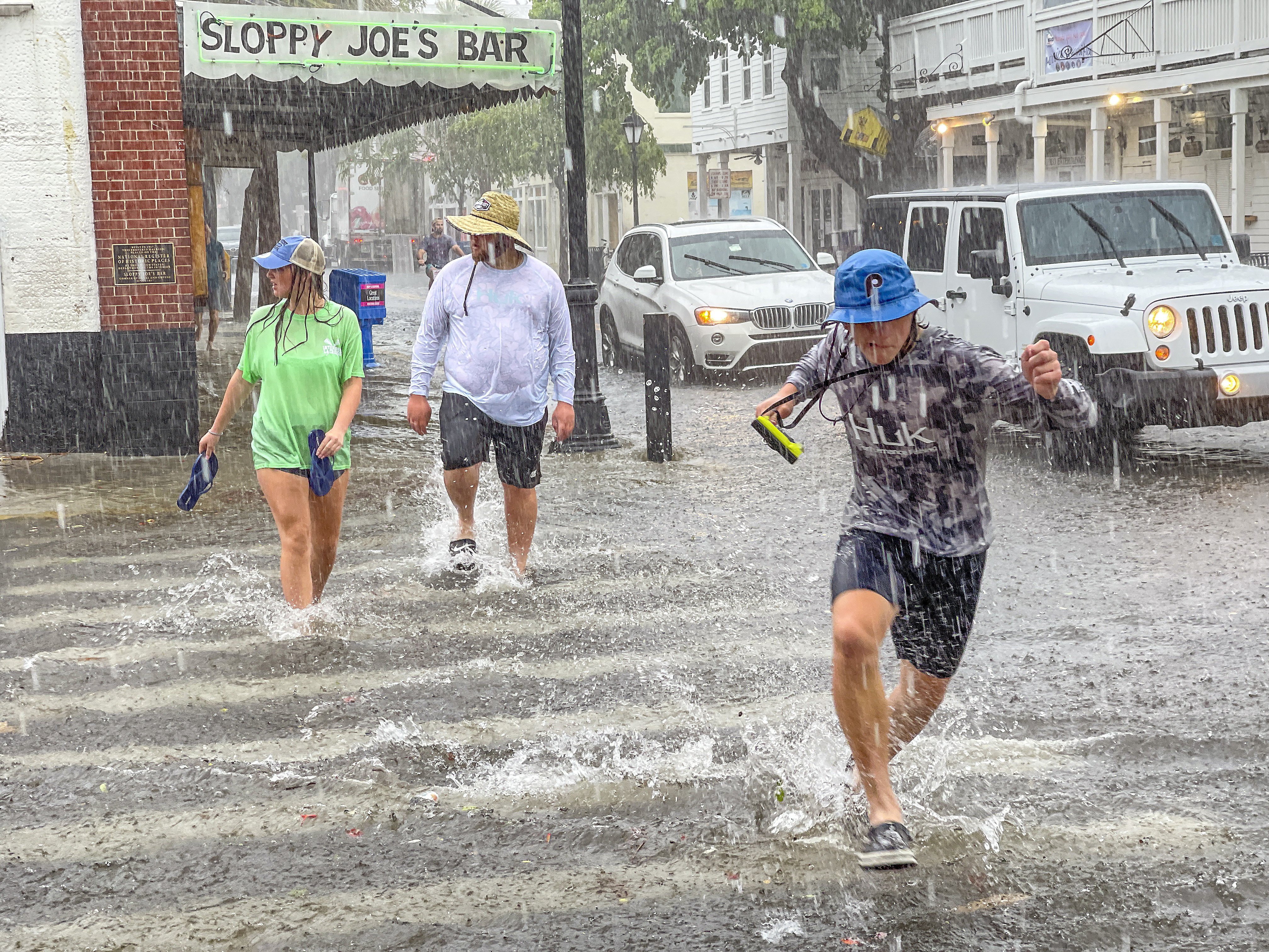 Pedestrians dash across the intersection of Greene and Duval streets as heavy winds and rain associated with Tropical Storm Elsa passes Key West, Florida, on Tuesday, July 6, 2021