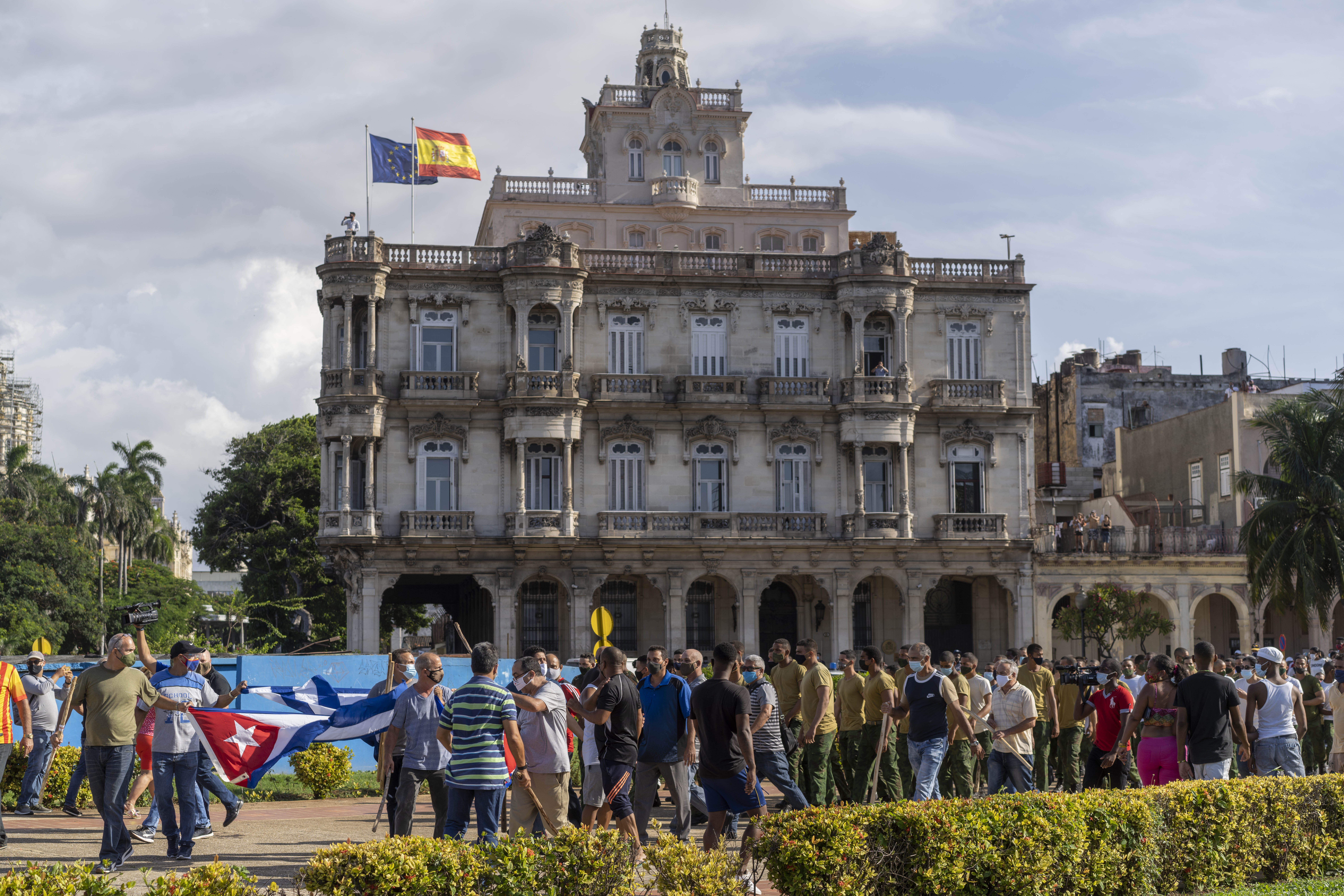 Government supporters march past the Embassy of Spain in Havana, Cuba, Sunday, July 11, 2021. Hundreds of demonstrators took to the streets in several cities in Cuba to protest against ongoing food shortages and high prices of foodstuffs