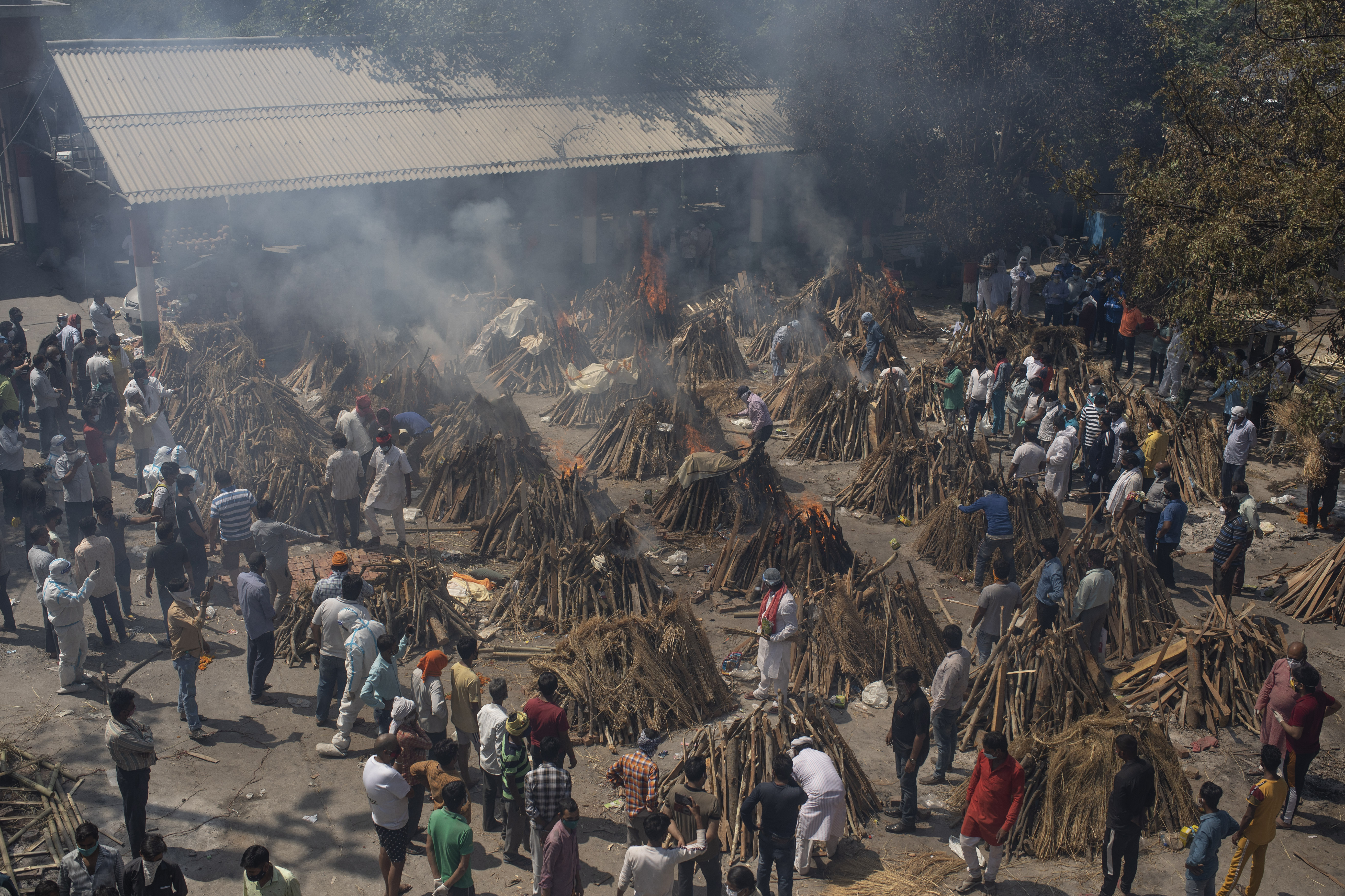 In this April 24, 2021 photo, multiple funeral pyres of those who died of COVID-19 burn at a ground that was converted into a crematorium in New Delhi