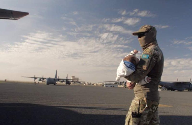 A Kazakh military officer is seen as he carries a child during the Zhusan humanitarian operation in 2019. [Astana Times]