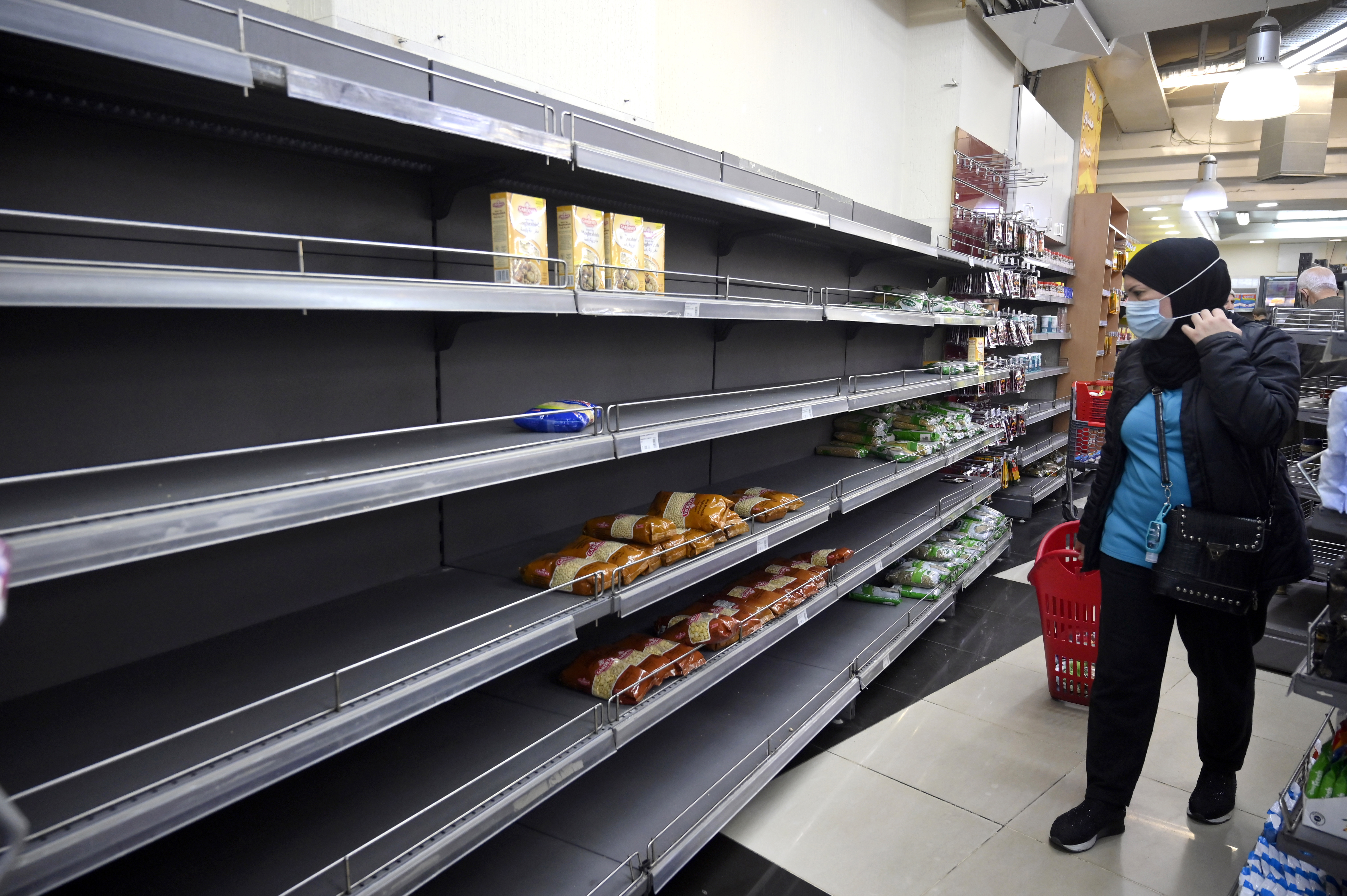 A customer walks past an almost empty shelf in a supermarket in Beirut, Lebanon, 24 March 2021.