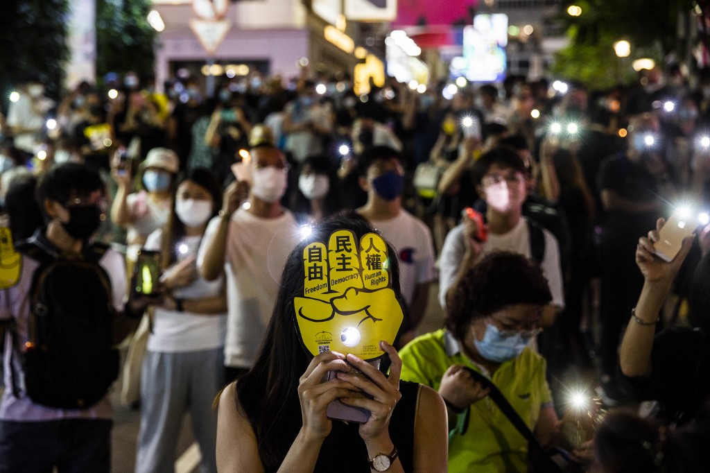People hold up their phones with the light on in the Causeway Bay district of Hong Kong on June 4, 2021, after police closed the venue where Hong Kong people traditionally gather each year to mourn the victims of China’s Tiananmen Square crackdown in 1989