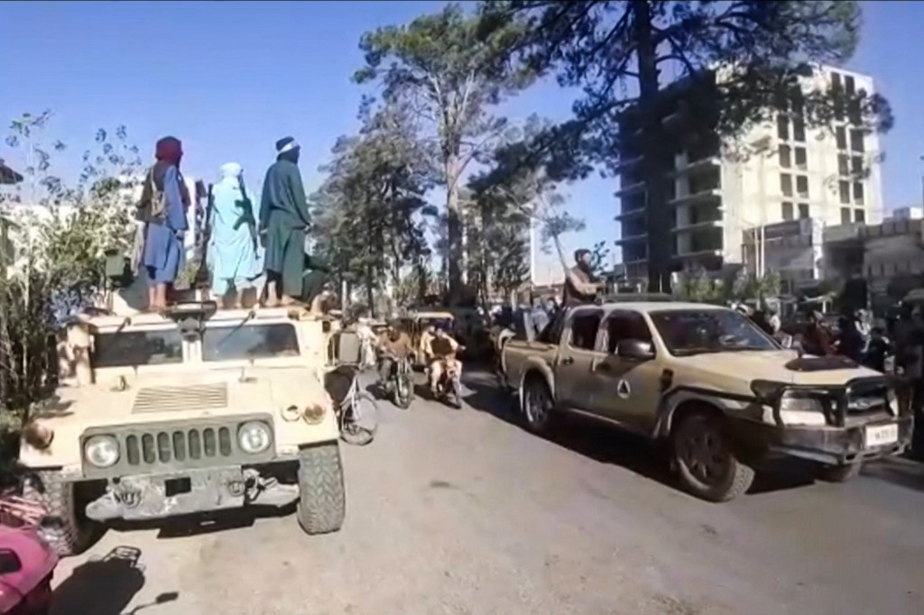 The Taliban fighters standing on a military vehicle in the streets of Herat
