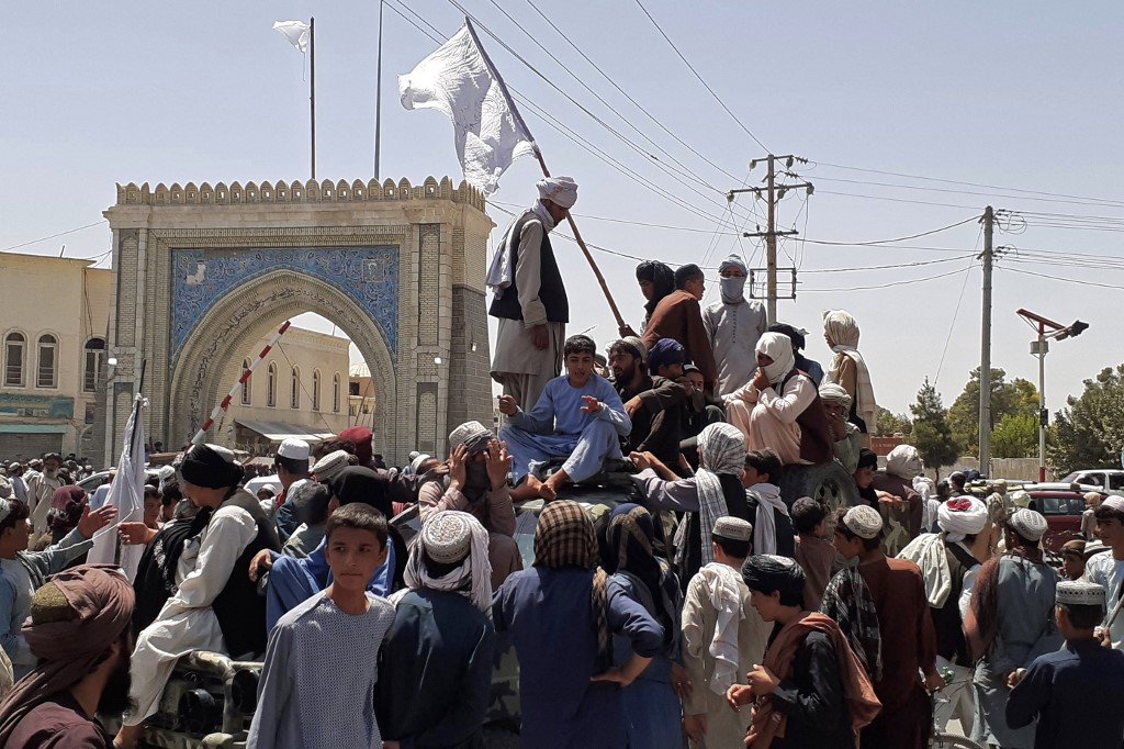 Taliban fighters stand on a vehicle along the roadside in Kandahar, Afghanistan [AFP]