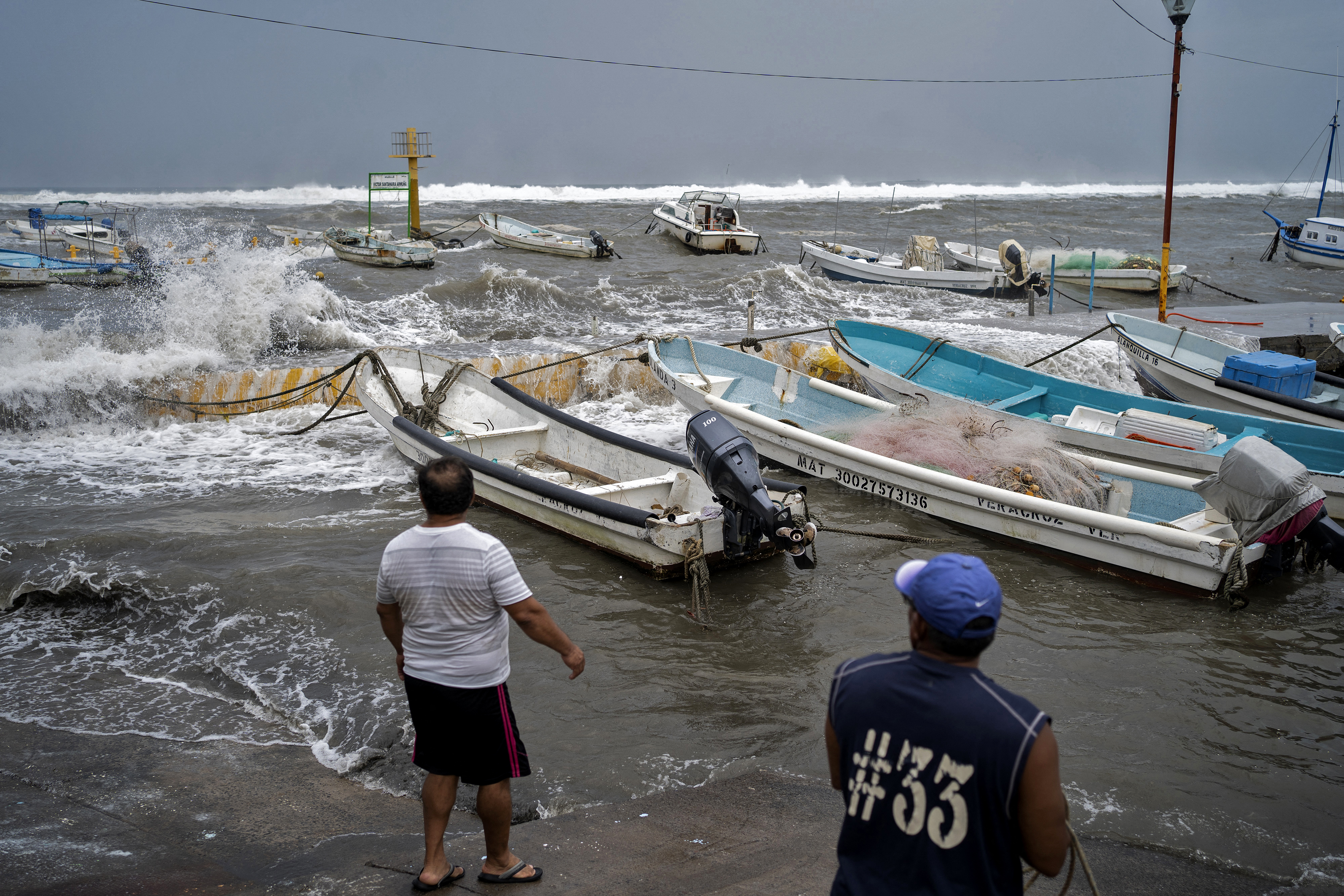 Fishermen prepare to remove boats from the dock as strong waves reach the coast due to Hurricane Grace