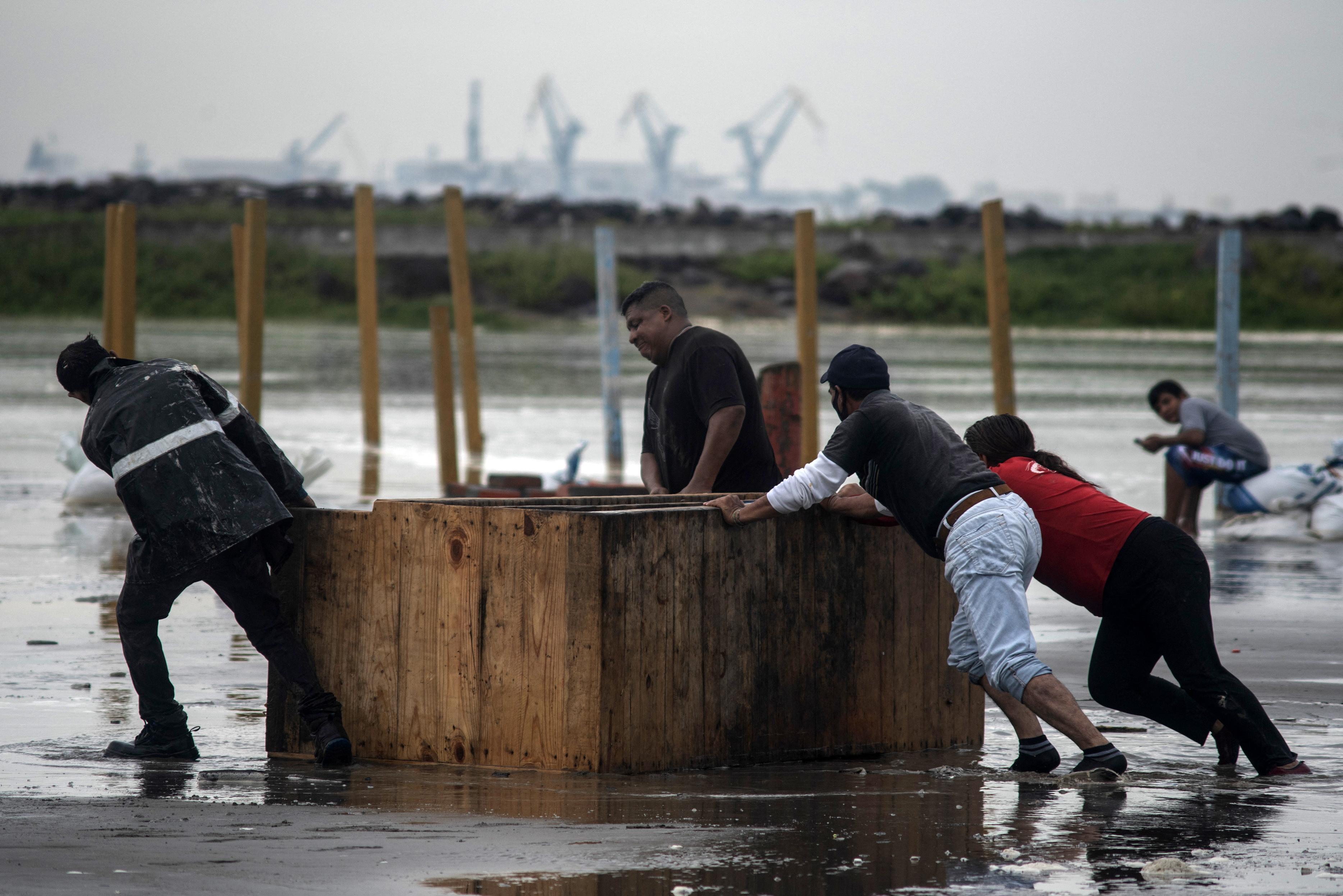 Workers remove furniture from the beach as strong waves reach the coast due to Hurricane Grace