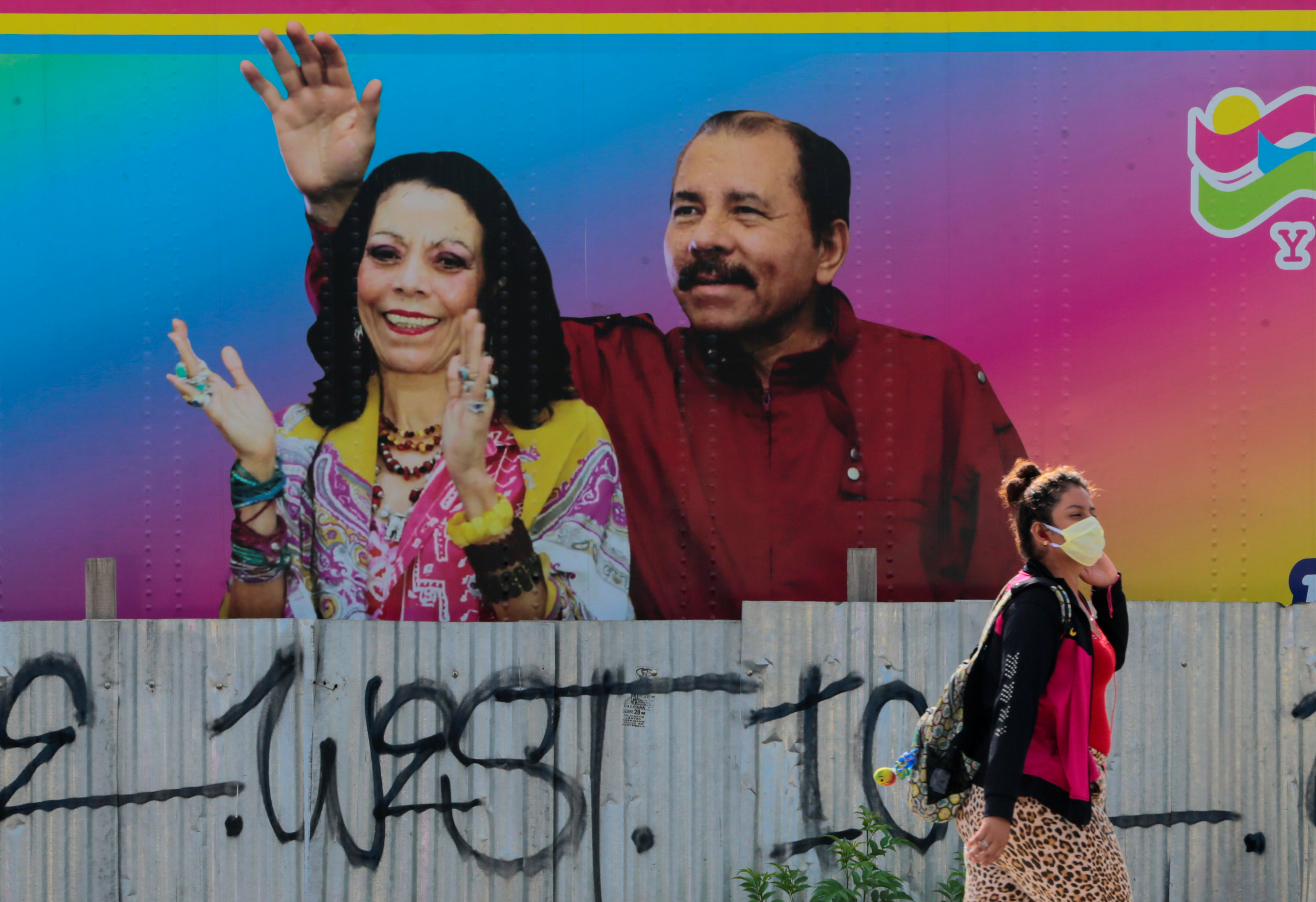 A woman stands in front of a billboard for Daniel Ortega