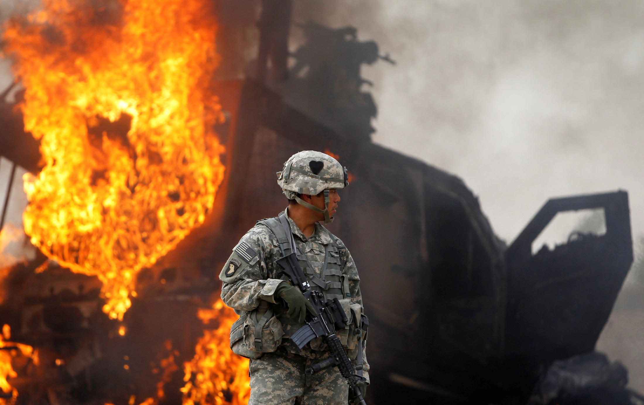 An American soldier stands near a burning M-ATV armoured vehicle after it struck an improvised explosive device in the Arghandab Valley north of Kandahar on July 23, 2010 [File: Reuters/Bob Strong]