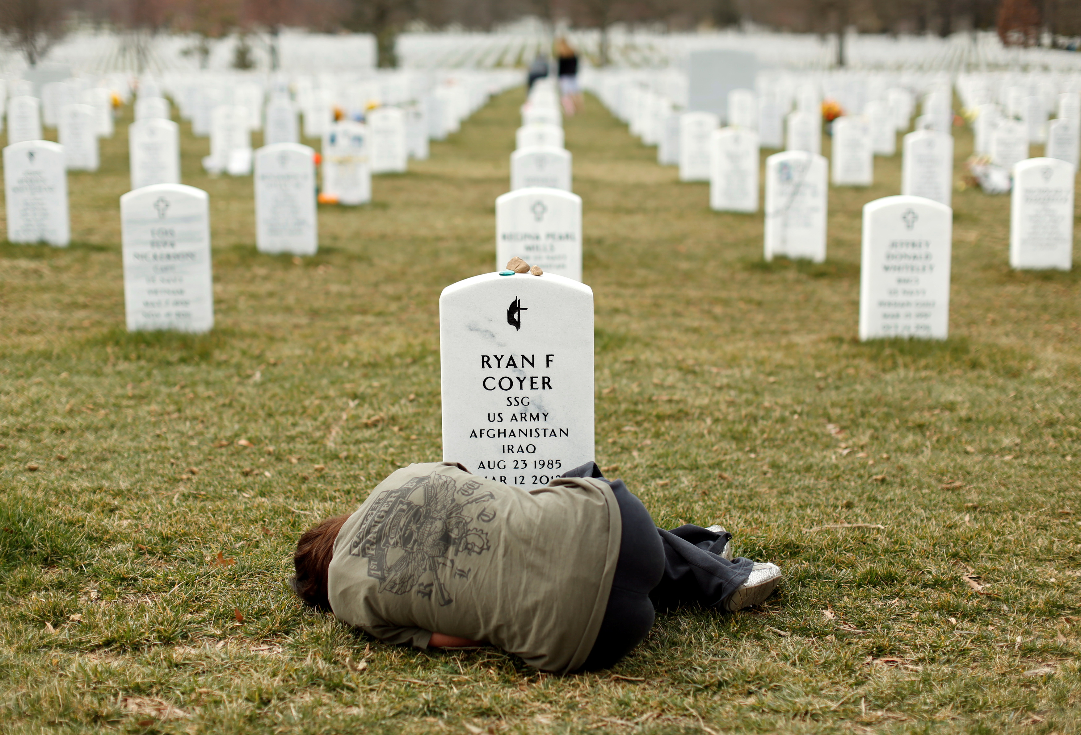 Lesleigh Coyer, of Saginaw, Michigan, lies down in front of the grave of her brother, Ryan Coyer, who served with the US Army in Iraq and Afghanistan, at Arlington National Cemetery