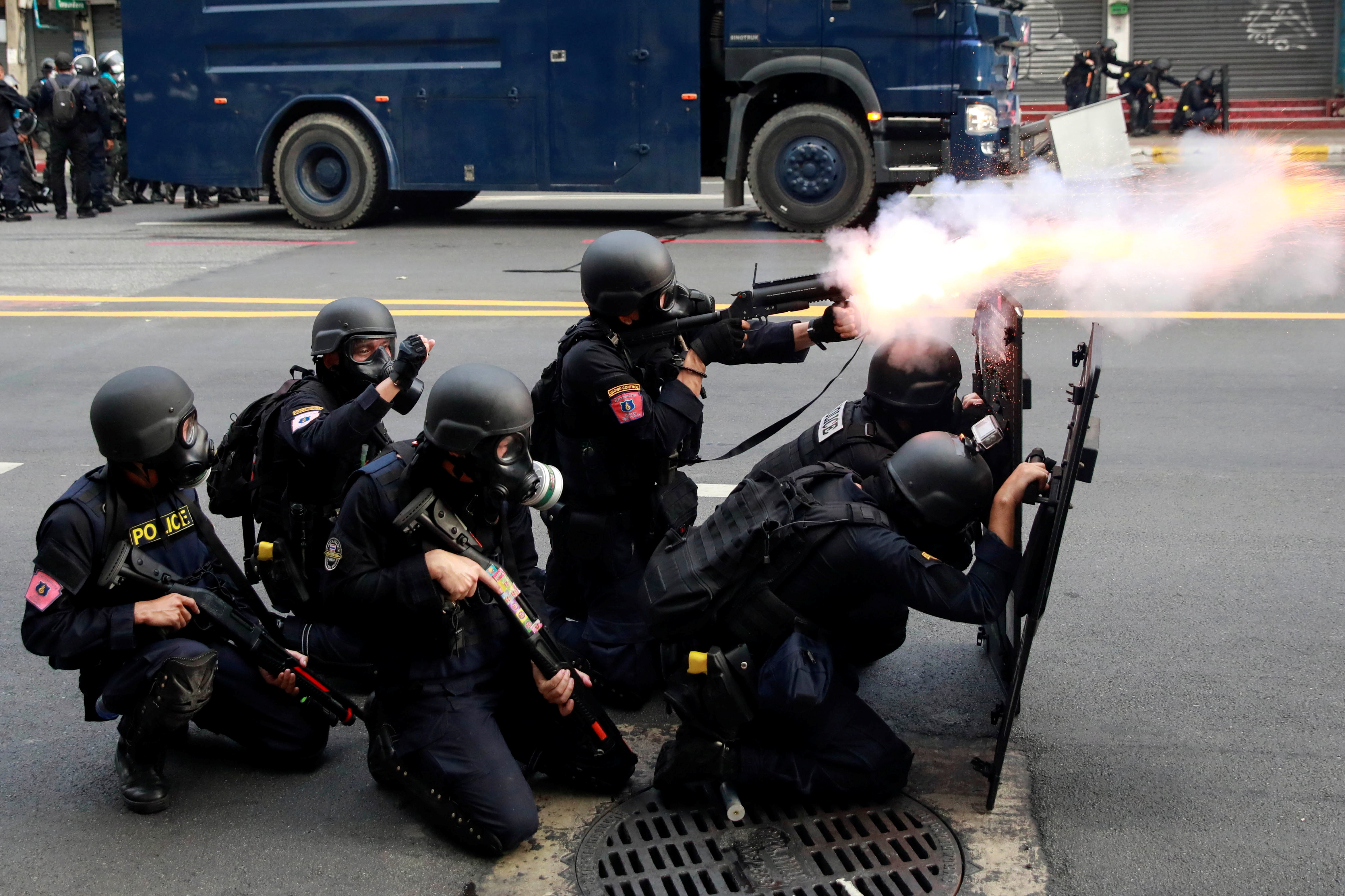 A police officer fires a weapon during clashes with demonstrators protesting against what they call the government’s failure in handling the coronavirus pandemic