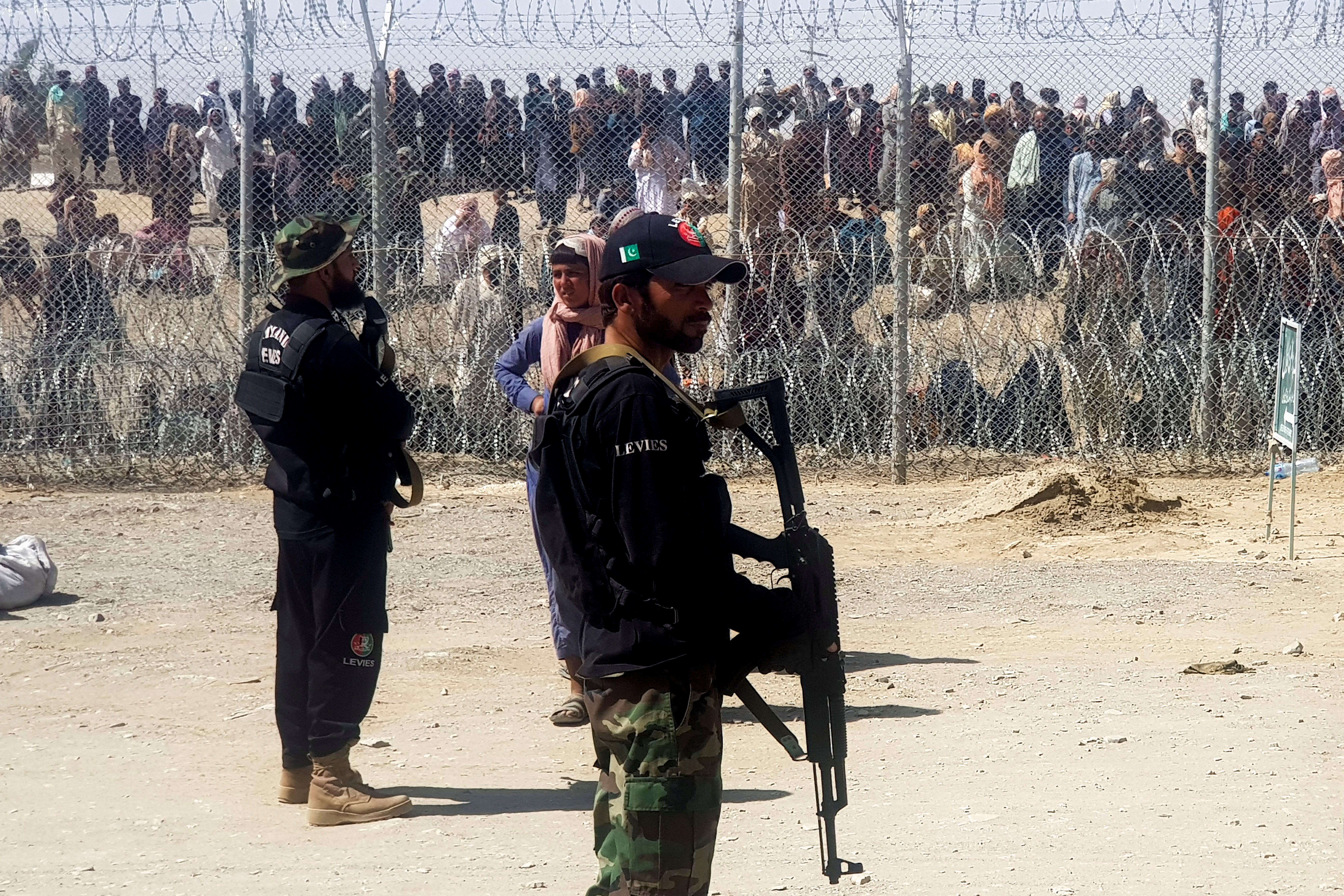 Pakistan’s paramilitary personnel stand guard in front of people who wait to cross at the Friendship Gate crossing point in the border town of Chaman