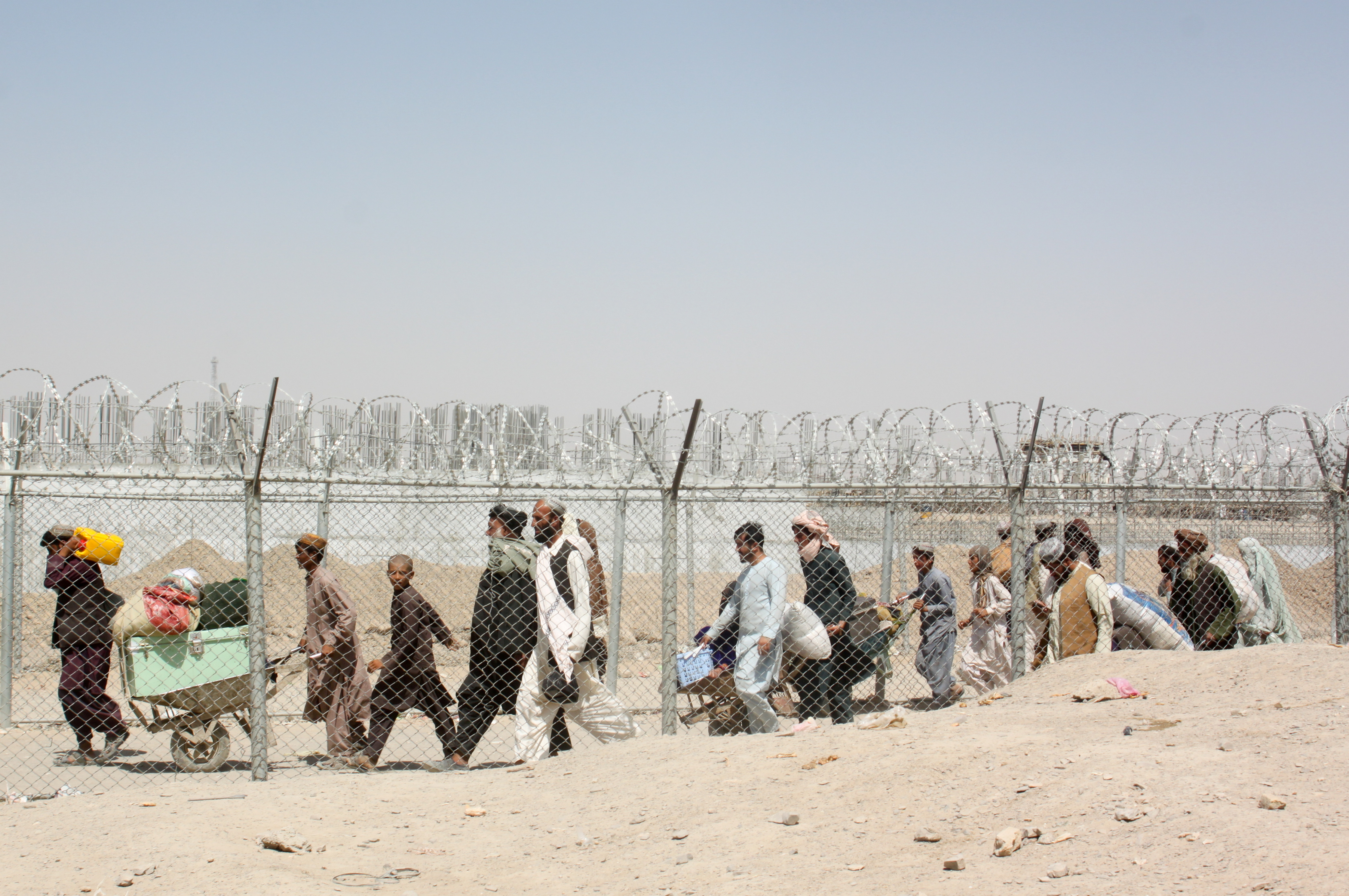 People arriving from Afghanistan cross the fence at the Friendship Gate crossing point, in the Pakistan-Afghanistan border town of Chaman, Pakistan August 18, 2021. [Abdul Khaliq Achakzai/Reuters]