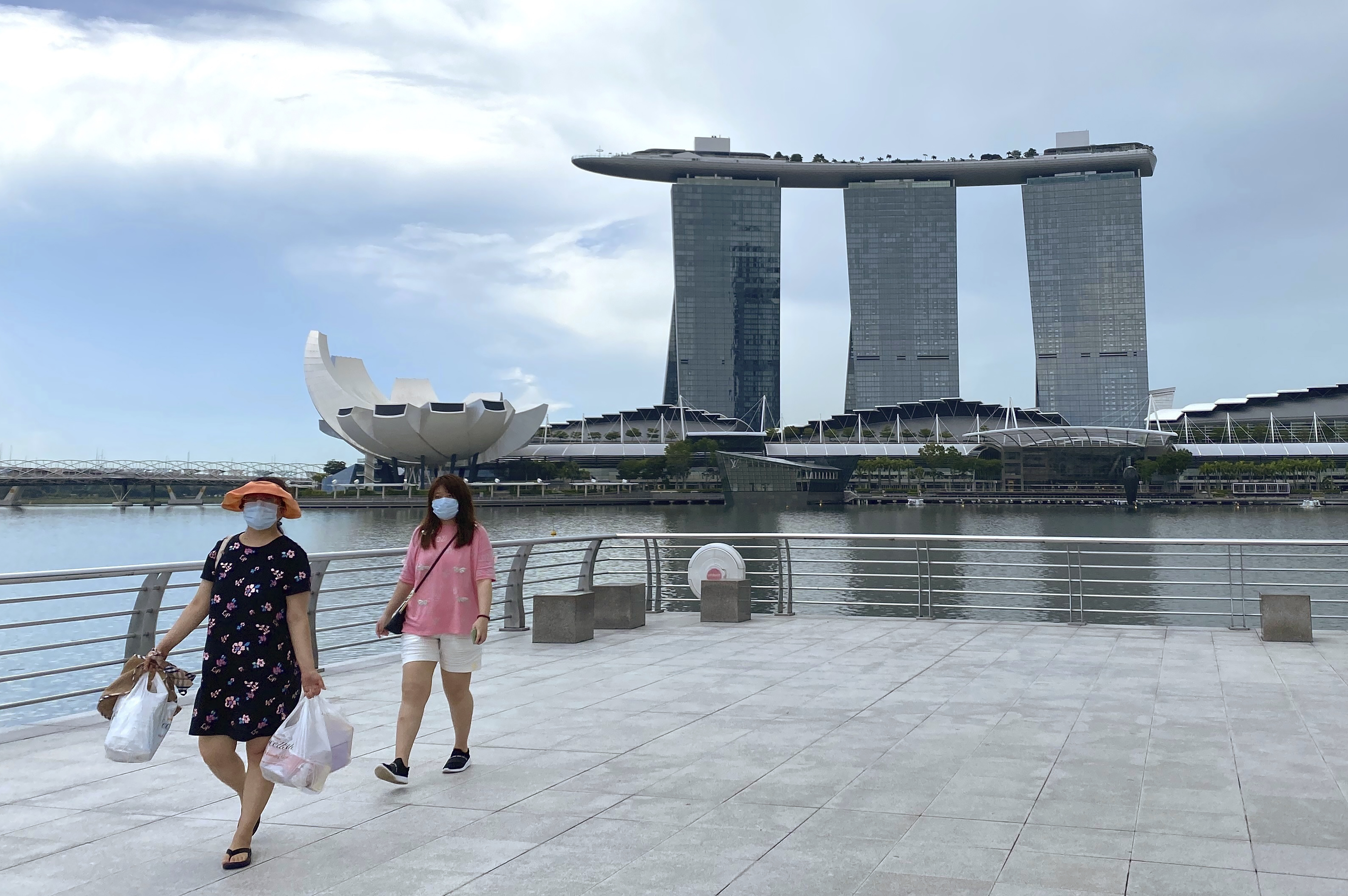 Visitors wearing masks walk in Merlion Park, a popular tourist spot, with the Marina Bay Sands in the background
