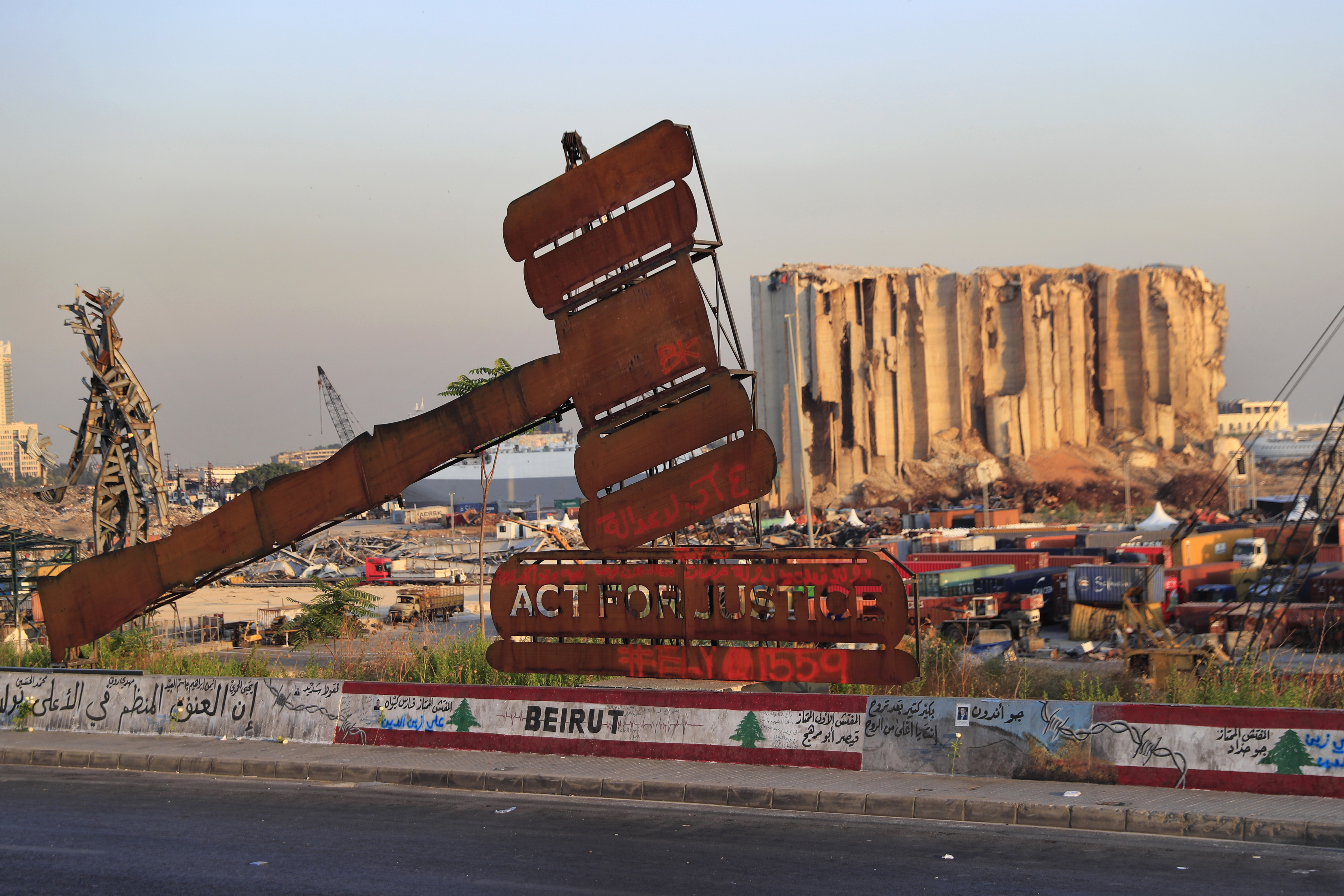 A justice symbol monument is seen in front of towering grain silos that were gutted in the enormous explosion at the port
